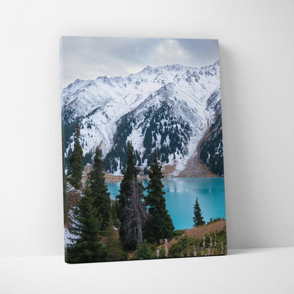 Snow-capped mountain canvas wall art with pine trees and turquoise lake in vertical orientation.