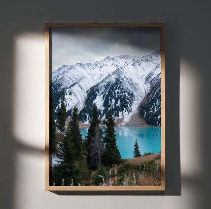 Majestic snow-capped mountain range poster with turquoise lake and evergreen trees, vertical wall art.
