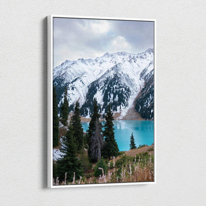 Vertical canvas wall art featuring snow-capped mountains with pine trees and a turquoise lake.