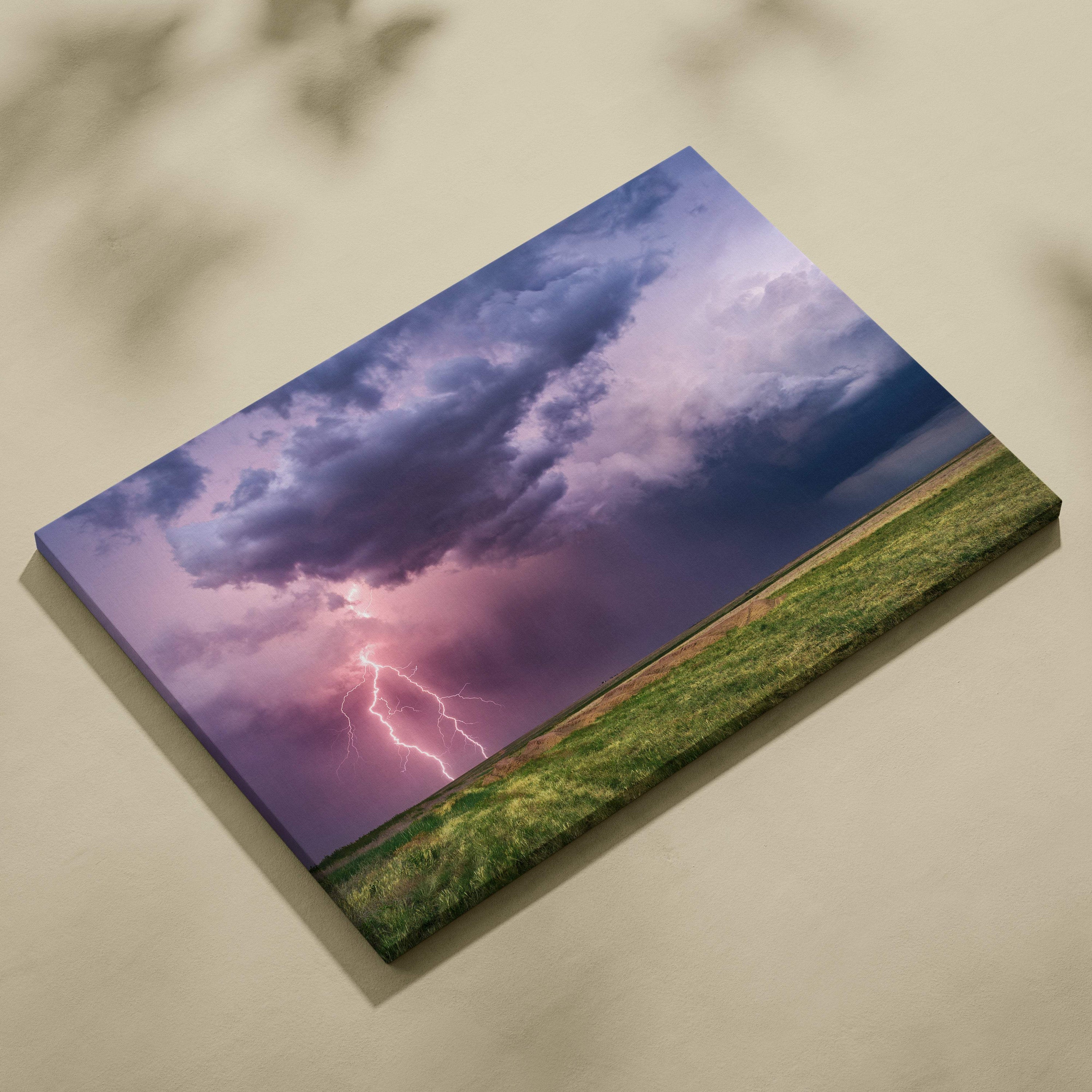 Canvas print of a dramatic lightning storm with purple and pink sky and electric bolt over a green field wall decor
