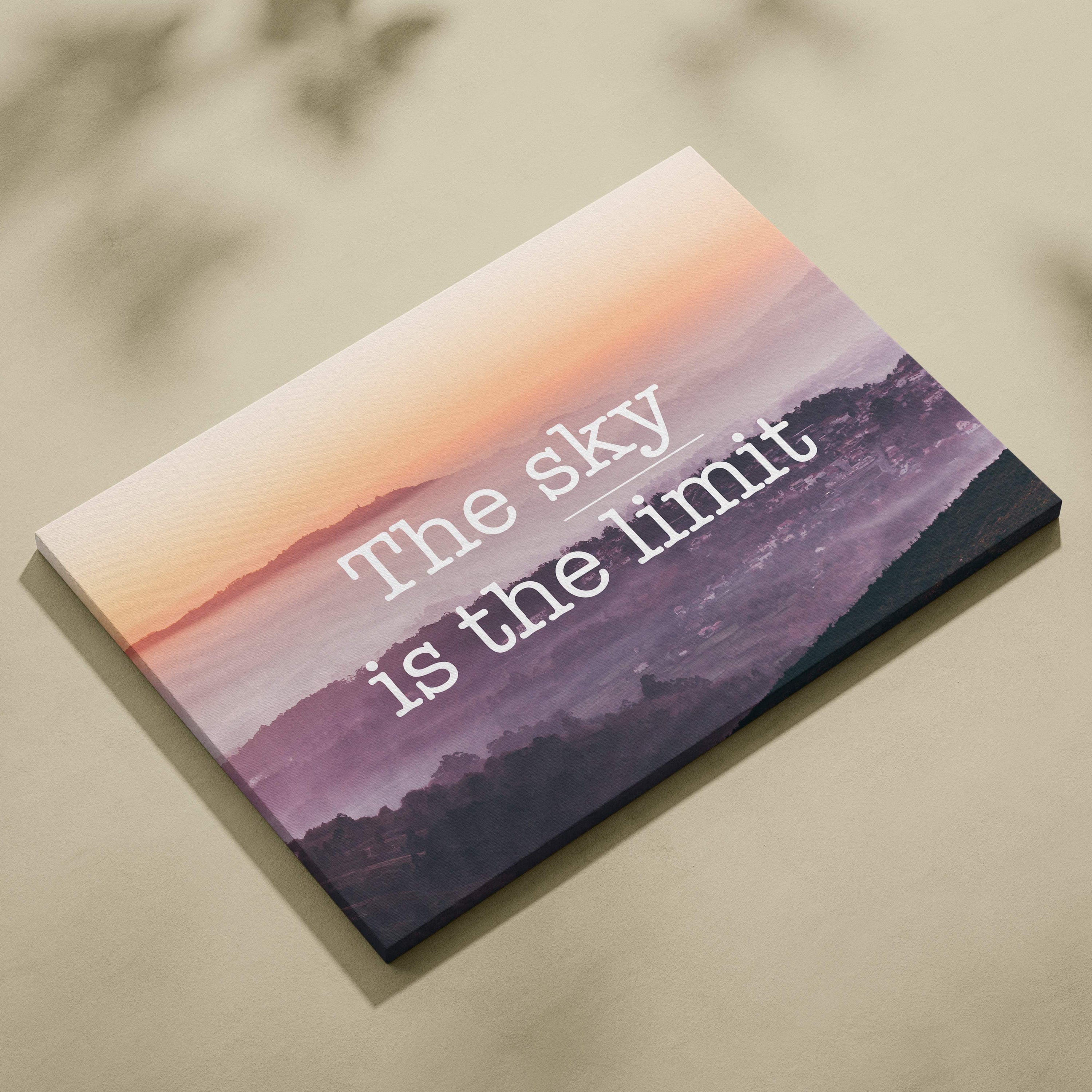 Rectangular canvas wall art featuring a pink purple gradient sunset over mountains with the sky is the limit quote in white text