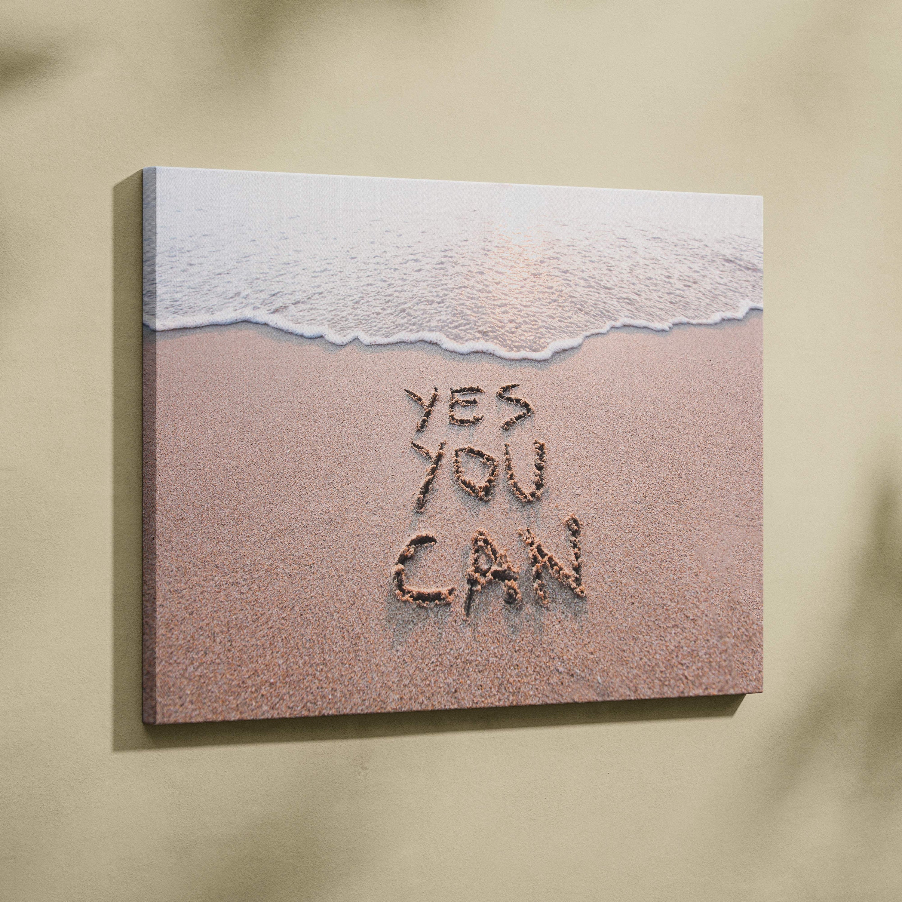 Beige canvas wall art featuring a beach scene with gentle waves and yes you can written in sand inspirational print