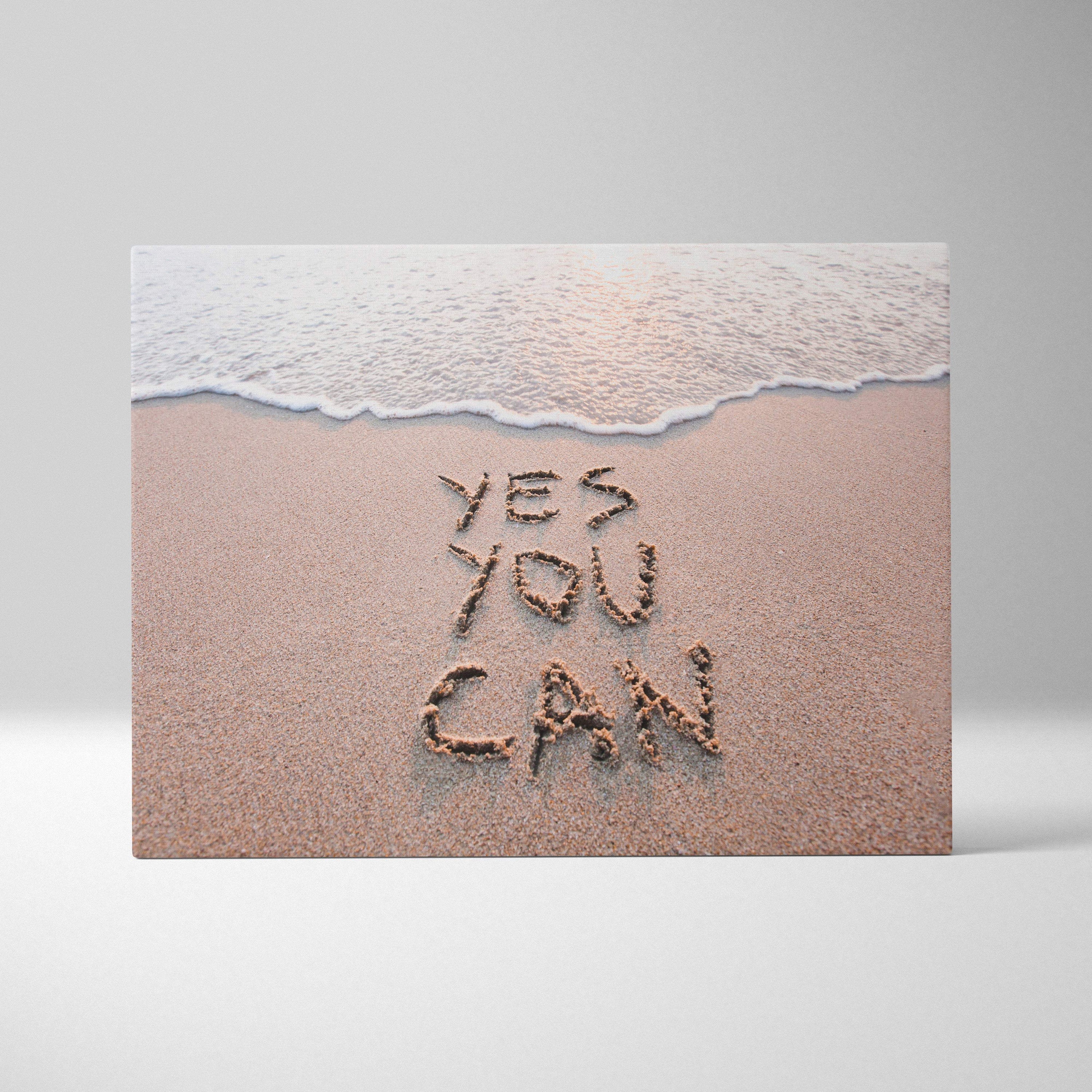Beige canvas print featuring yes you can written in sand with gentle wave motivational beach wall art decor