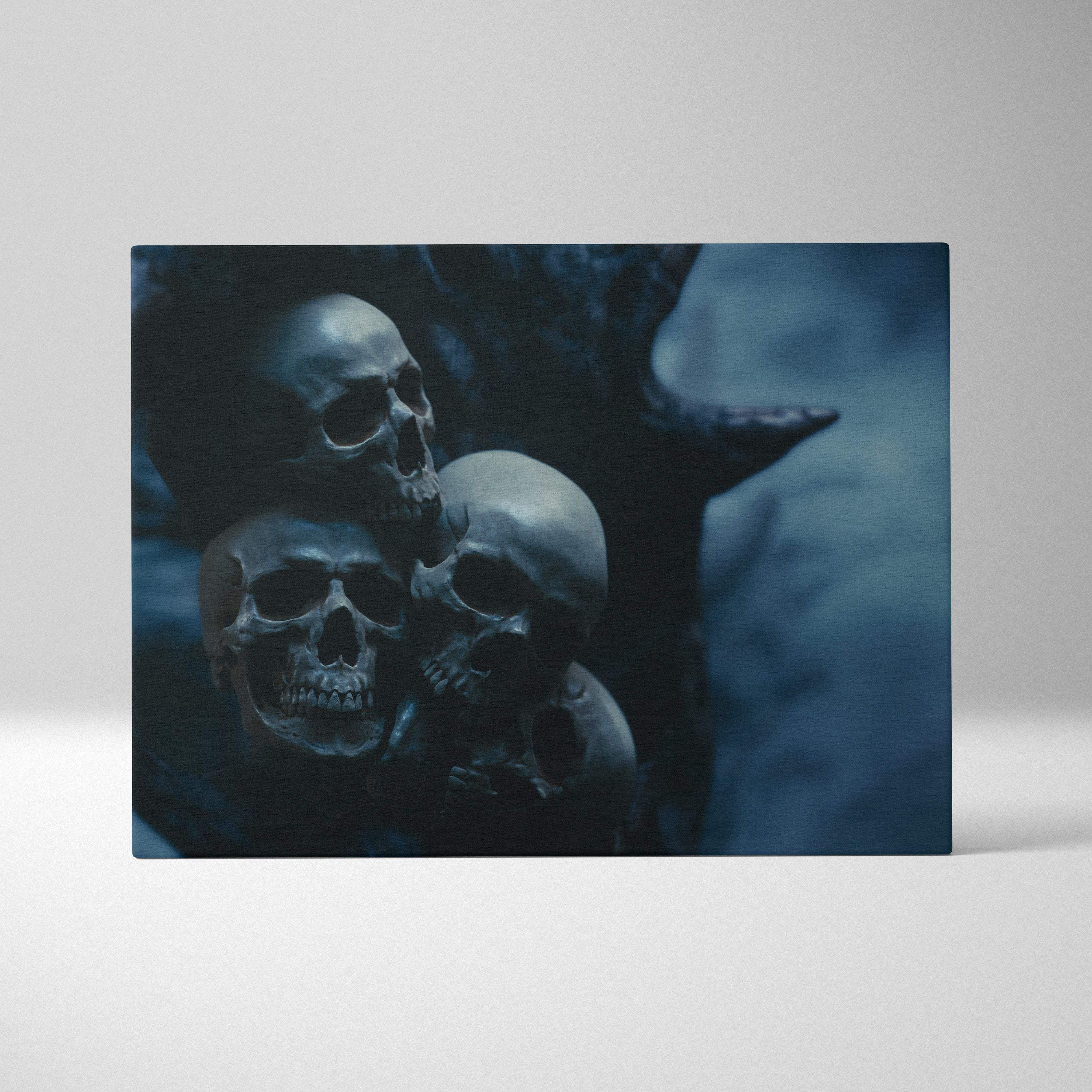 Dark blue rectangular canvas wall art print featuring a moody image of three stacked skulls with tree silhouette for gothic decor