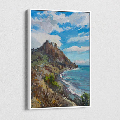 A framed coastal mountain canvas print of a turquoise ocean cliff with greenery and vibrant blue sky wall art