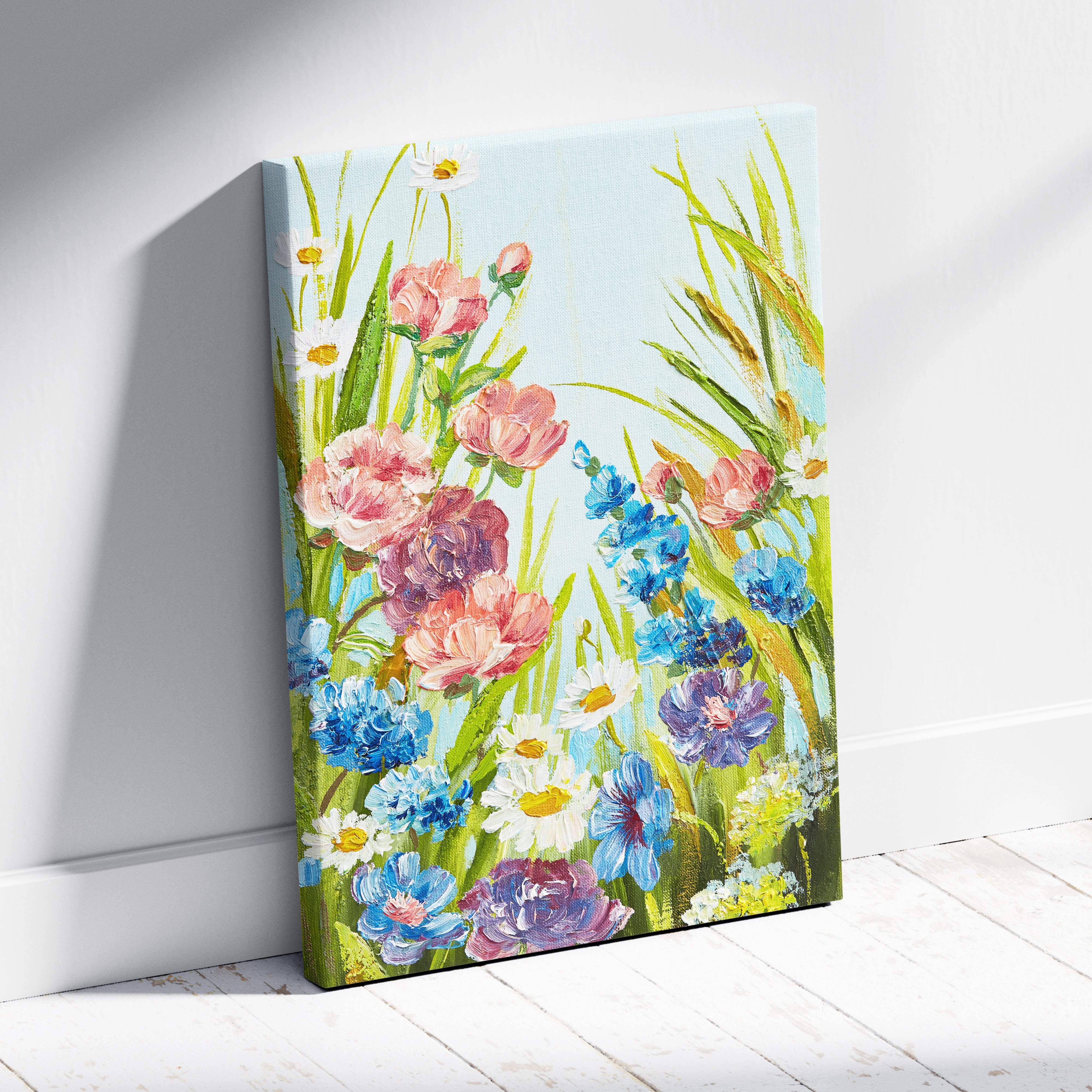 A vibrant floral canvas wall art with pink blue and white blossoms and green grass on a light sky background
