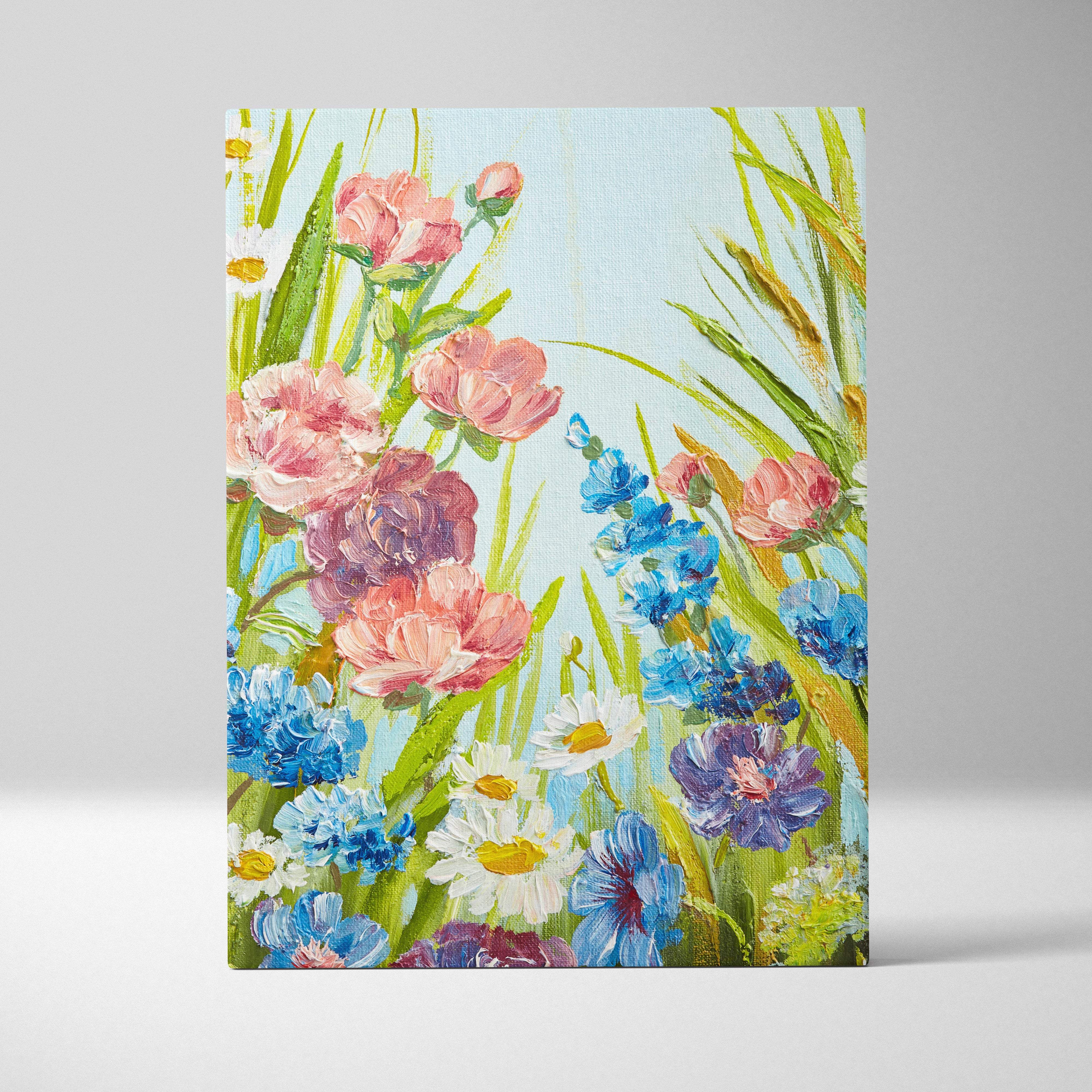 A vibrant canvas wall art painting featuring blue pink wildflowers and green grass against a light blue sky