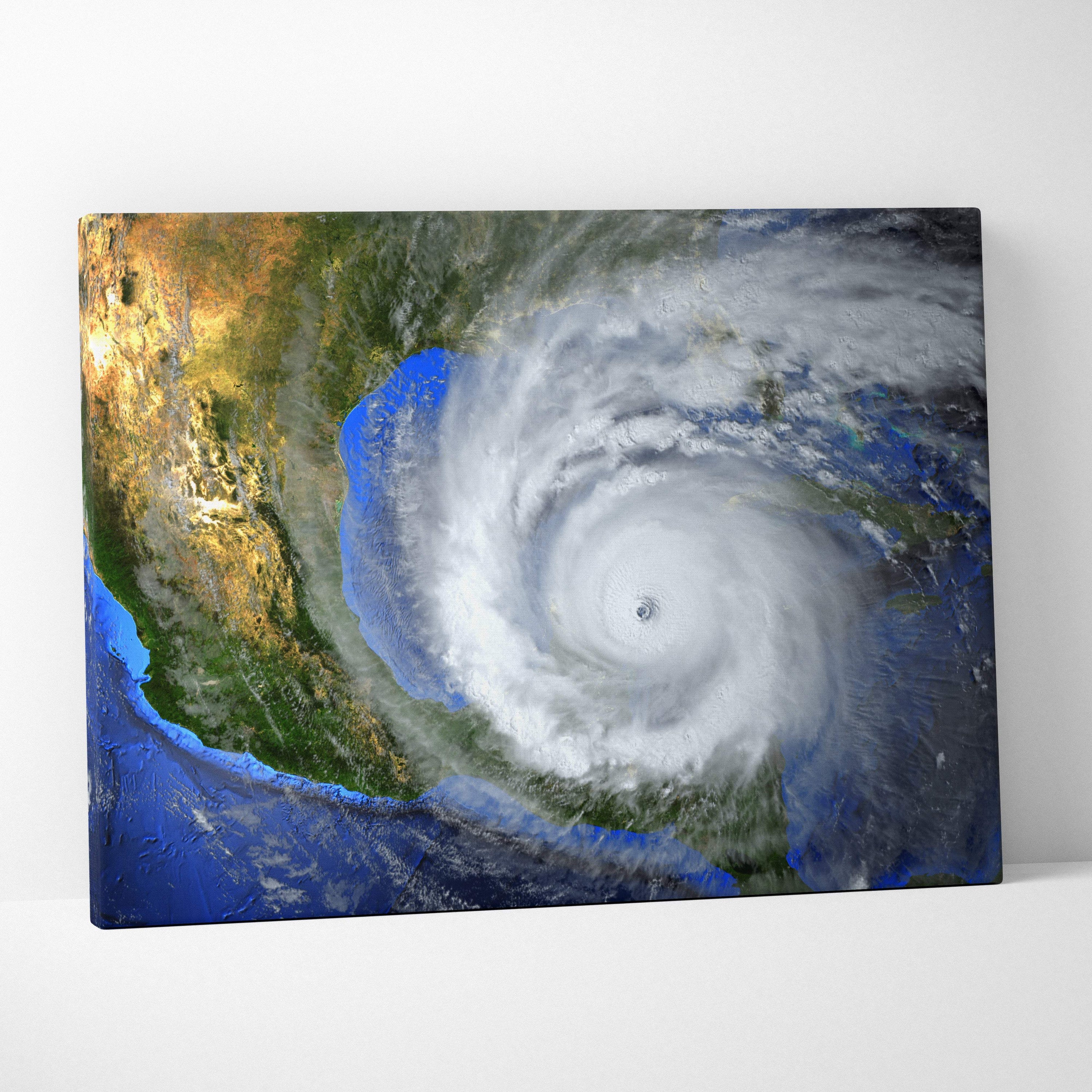 A rectangular canvas print of a massive hurricane swirling over a deep blue ocean with white spiral storm clouds and green landmasses