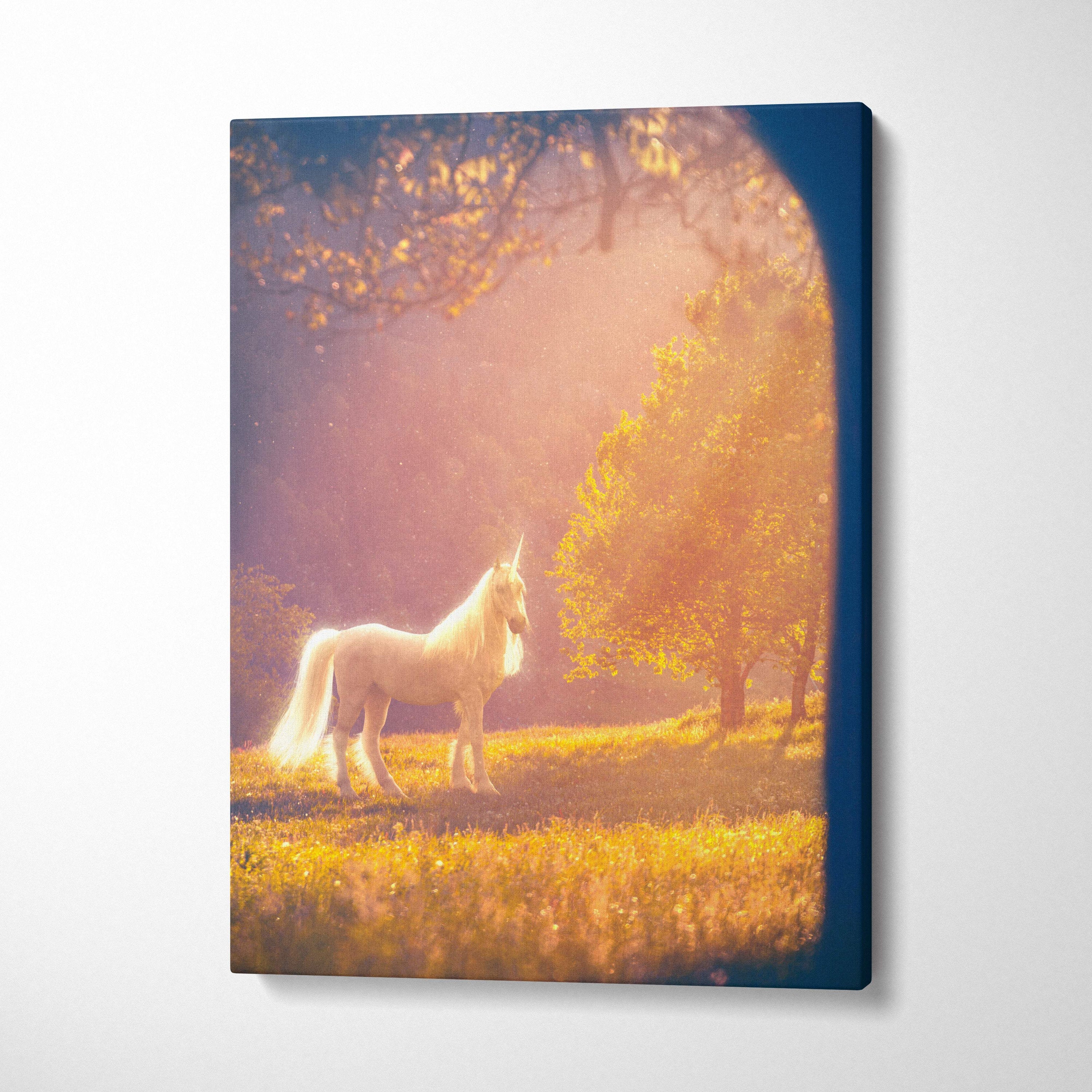 A rectangular canvas print of a white unicorn in a sunlit meadow with a dark blue border ethereal nature wall art
