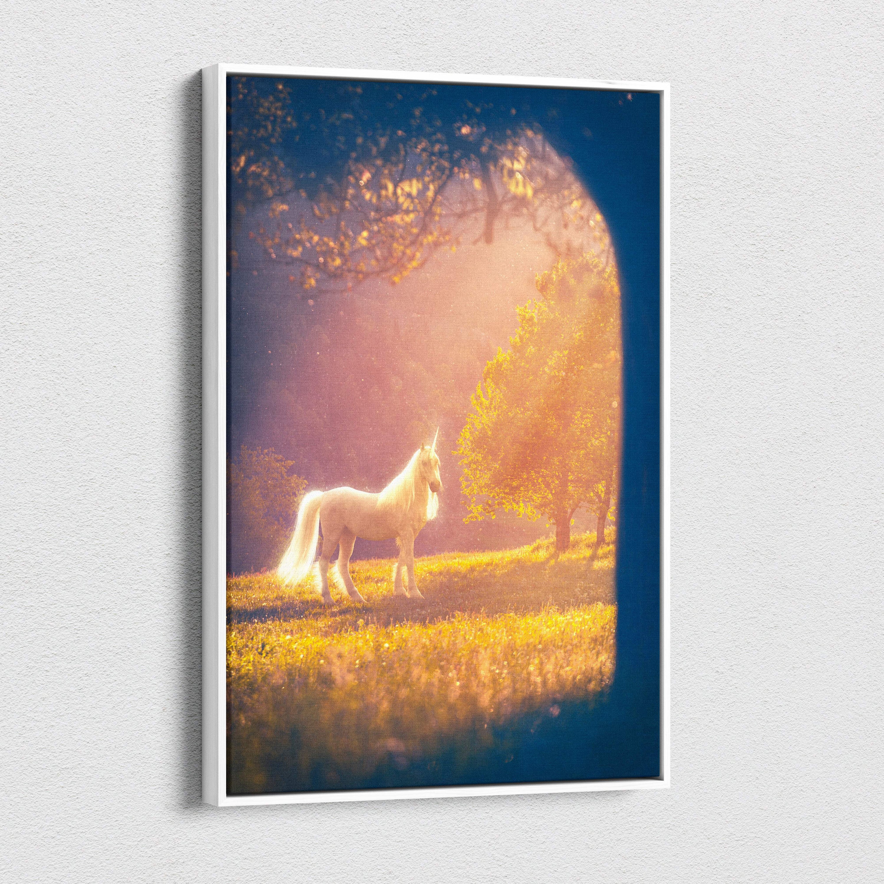 White-framed canvas print of a luminous white unicorn standing in a golden meadow under warm sunlight