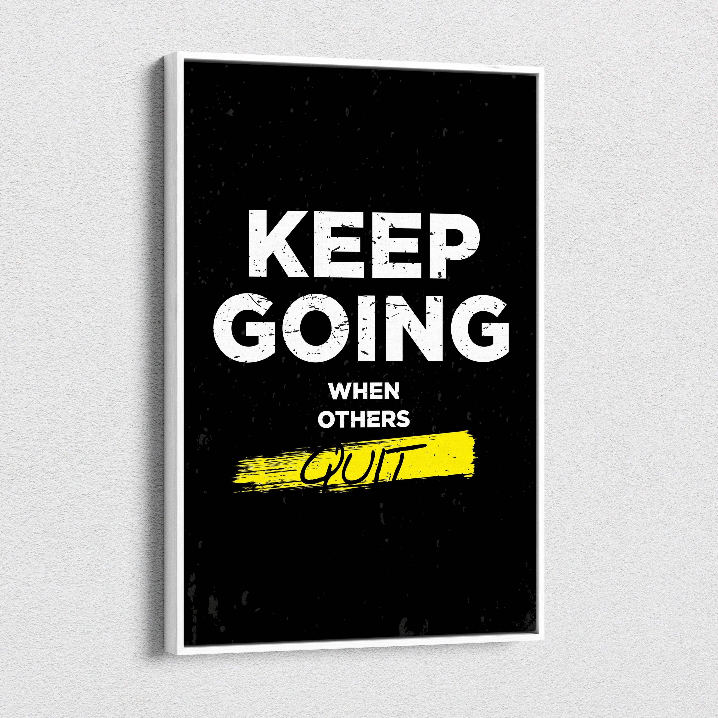 Black framed motivational canvas print with bold white keep going when others quit text and yellow brushstroke accent