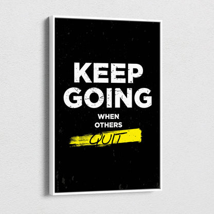 Black framed motivational canvas print with bold white keep going when others quit text and yellow brushstroke accent