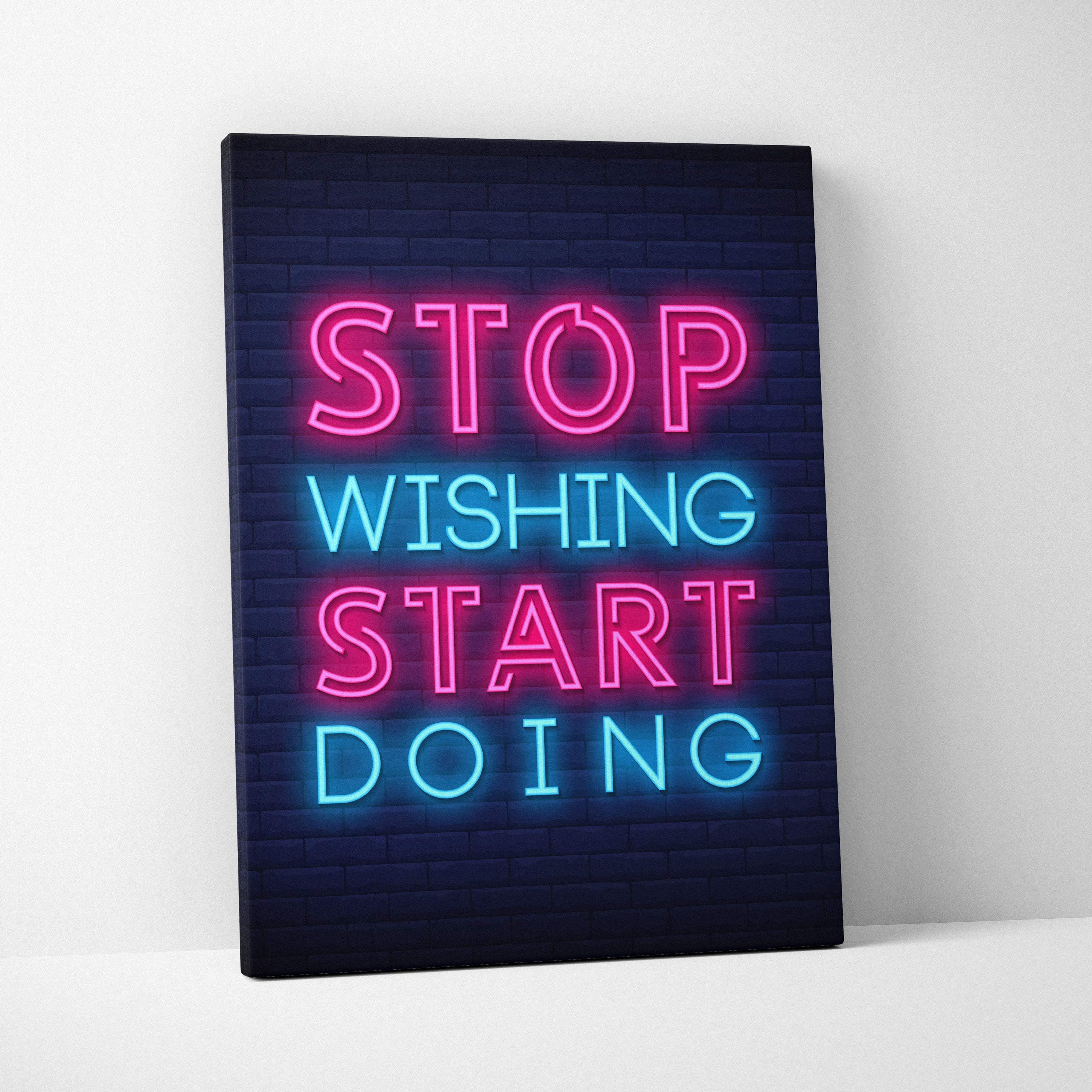 Neon pink and blue illuminated canvas print with stop wishing start doing motivational quote on dark brick background
