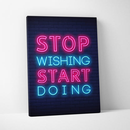 Neon pink and blue illuminated canvas print with stop wishing start doing motivational quote on dark brick background