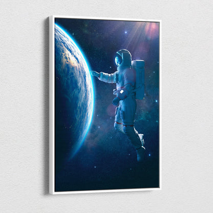 A framed blue cosmic space scene canvas featuring a white-suited astronaut reaching toward earth against stars