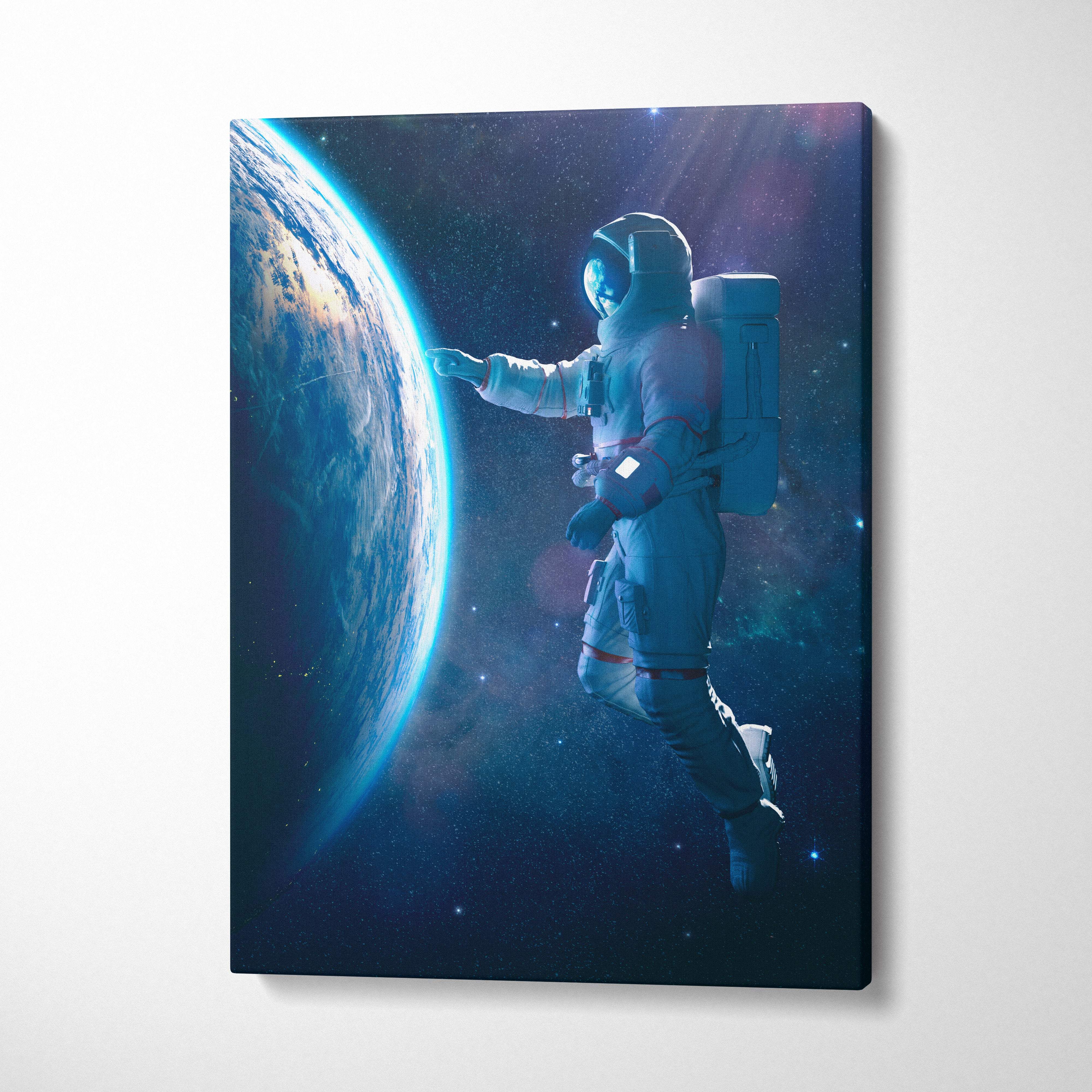 Canvas print of astronaut in white spacesuit with red accents floating near earth in blue cosmic space scene