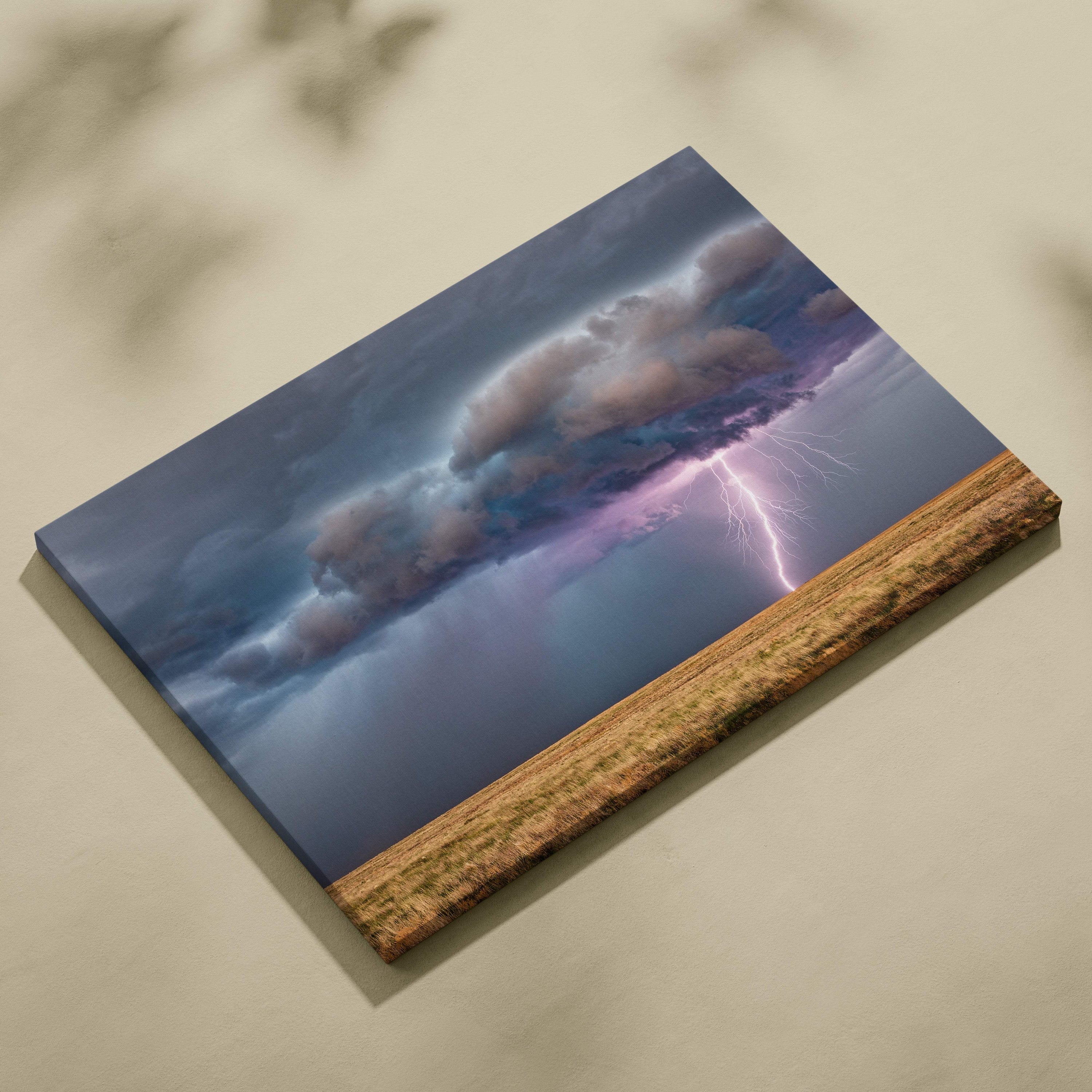 Canvas print of a dramatic lightning strike over golden prairie with moody blue clouds and purple flash wall decor