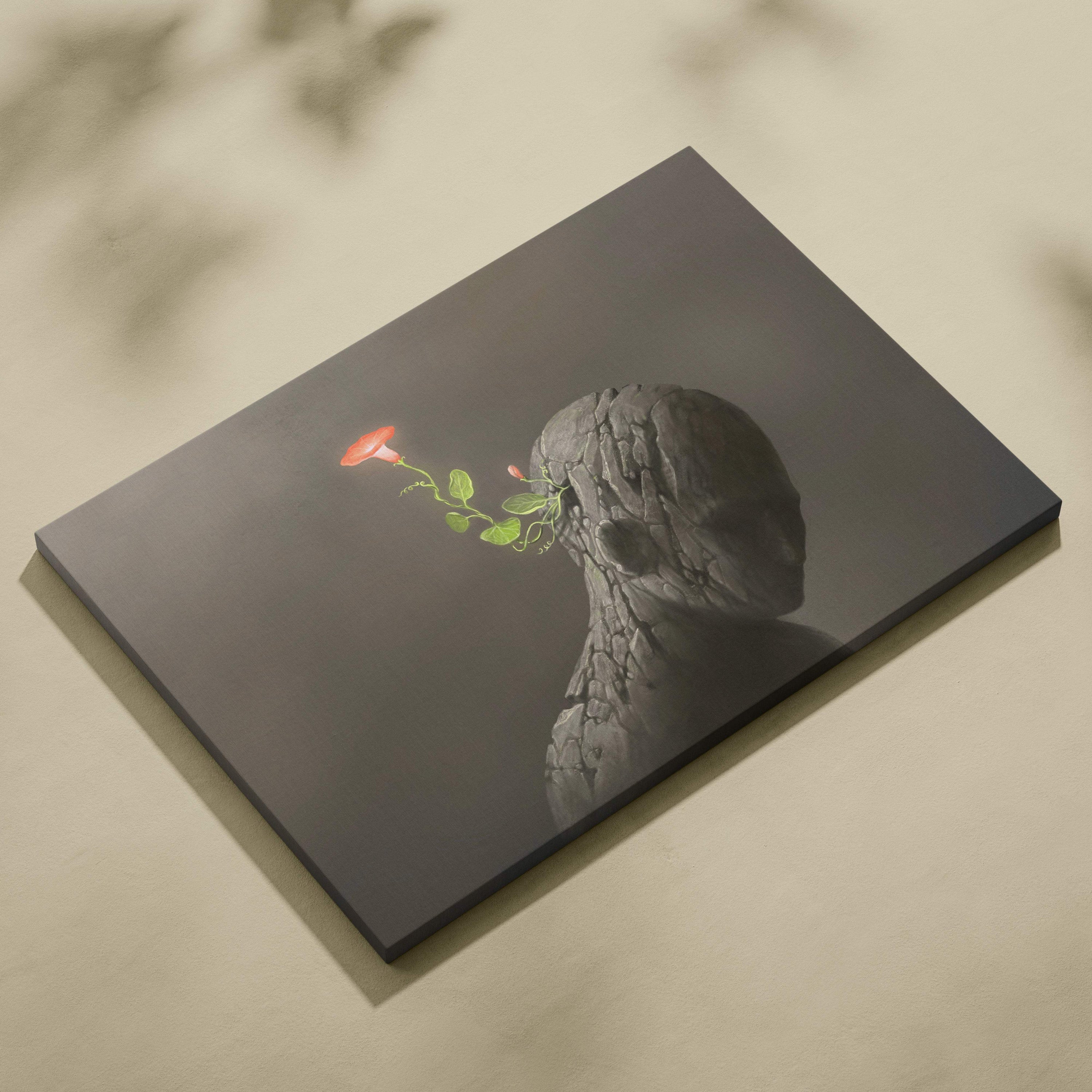 Dark gray canvas print of a cracked stone head with a vibrant red flower and green stem for modern wall art decor