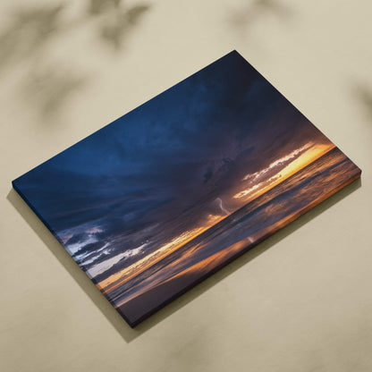 Canvas print of a dramatic stormy ocean sunset with deep blue clouds and golden light reflecting on the sea