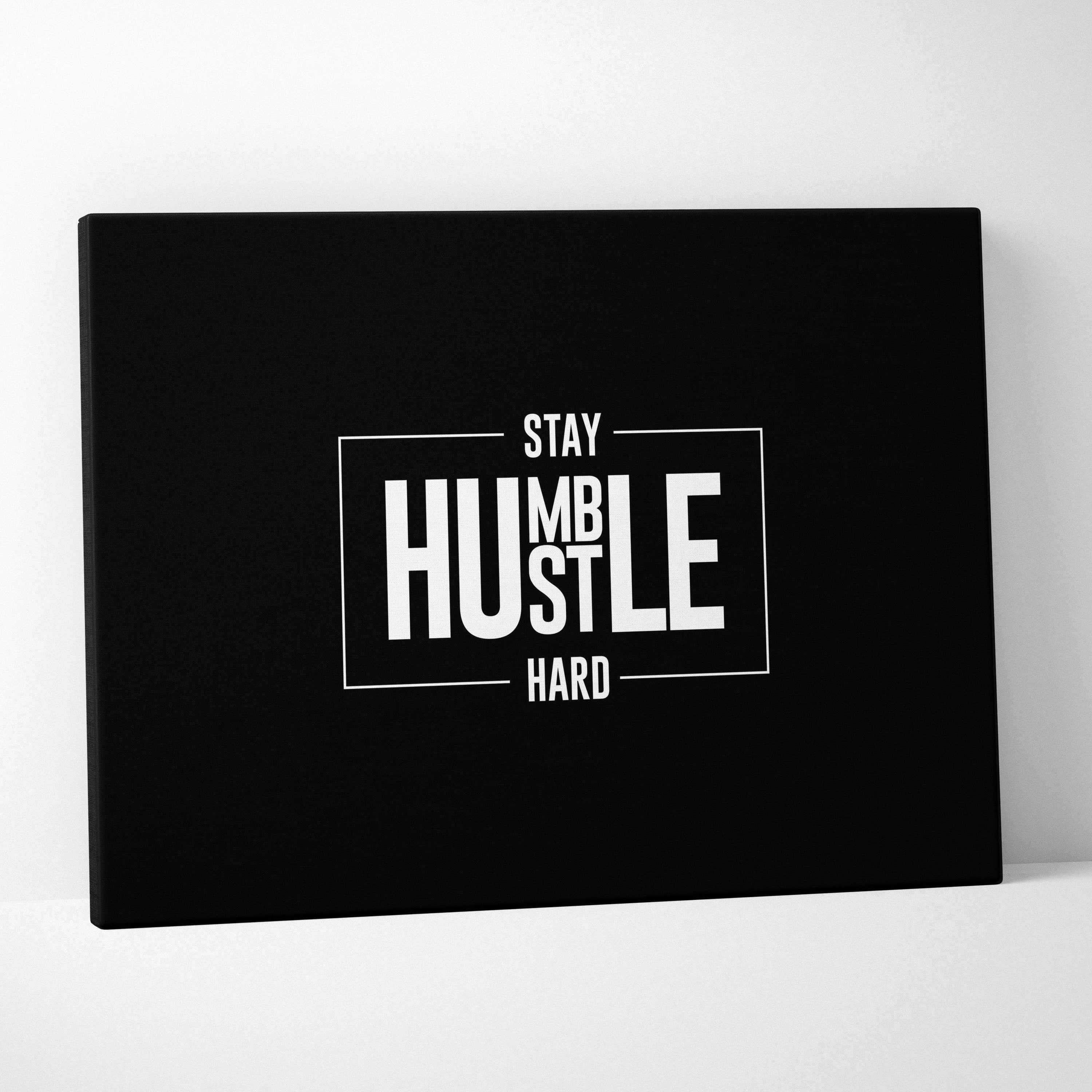 Black canvas print featuring stay humble hustle hard in bold white lettering within minimalist rectangular frame for office decor