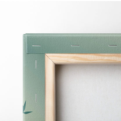 A sage green canvas wall art with light wood border and stitched detailing featuring a bamboo sunset design