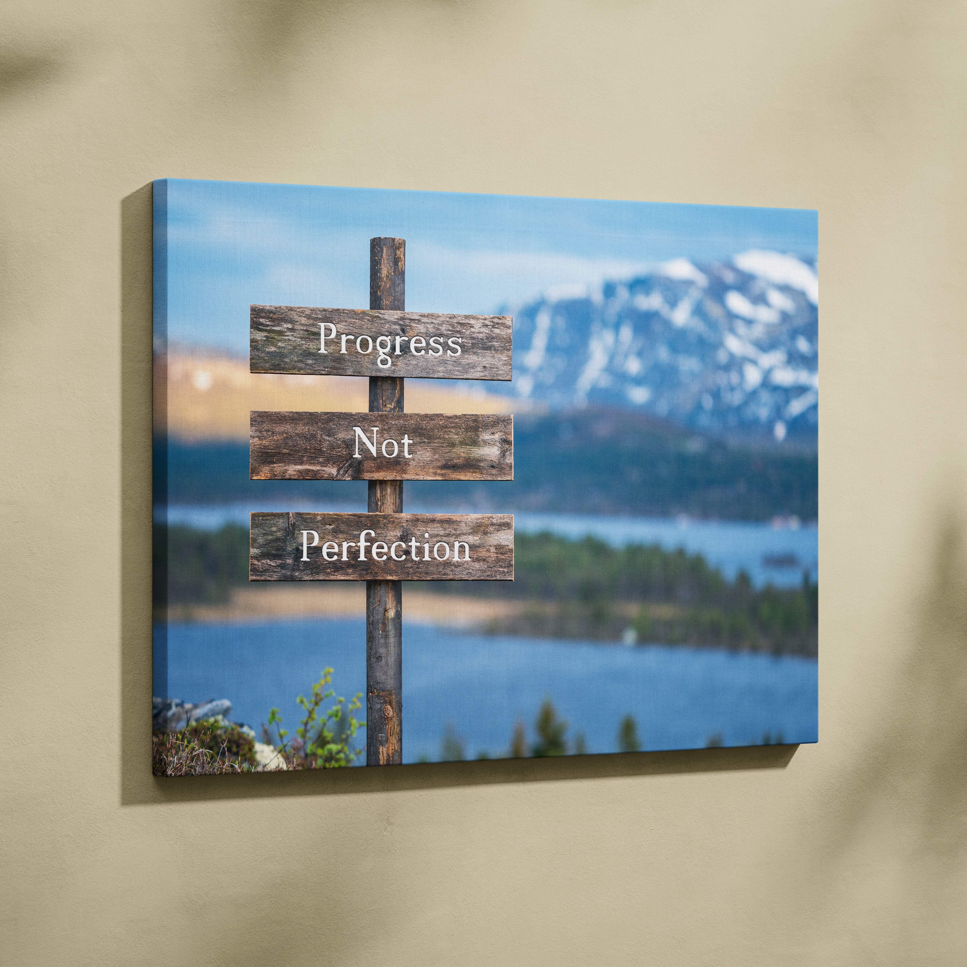 Rustic wooden canvas wall art with progress not perfection text on weathered planks over mountain lake backdrop