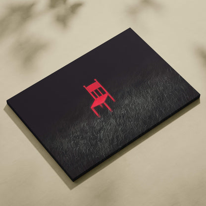 Black canvas print featuring a bold red minimalist chair silhouette on a textured grassy field background wall art