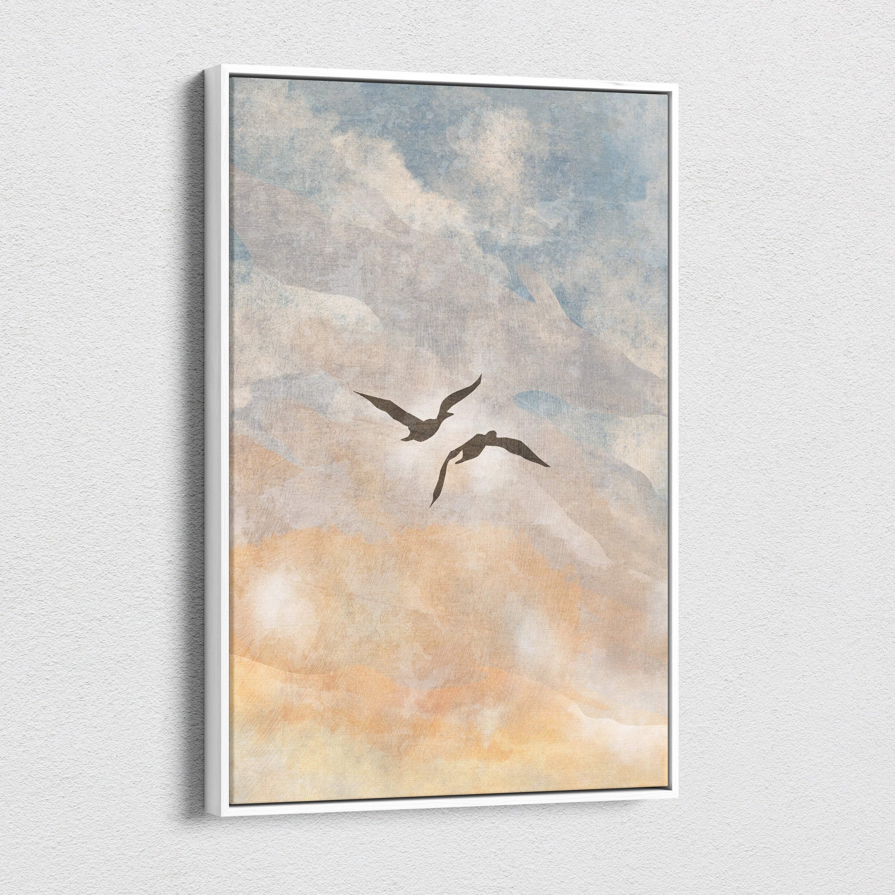 A framed canvas print of two dark silhouetted birds in flight against a soft blue peach and neutral watercolor sky