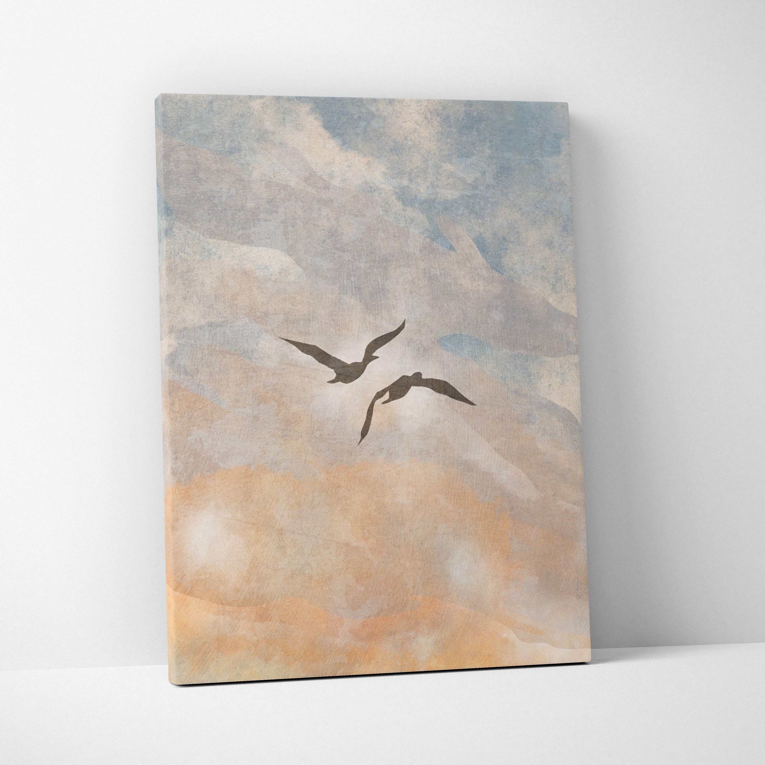 A rectangular canvas print of two dark silhouetted birds flying against a soft blue peach textured sky for boho coastal decor