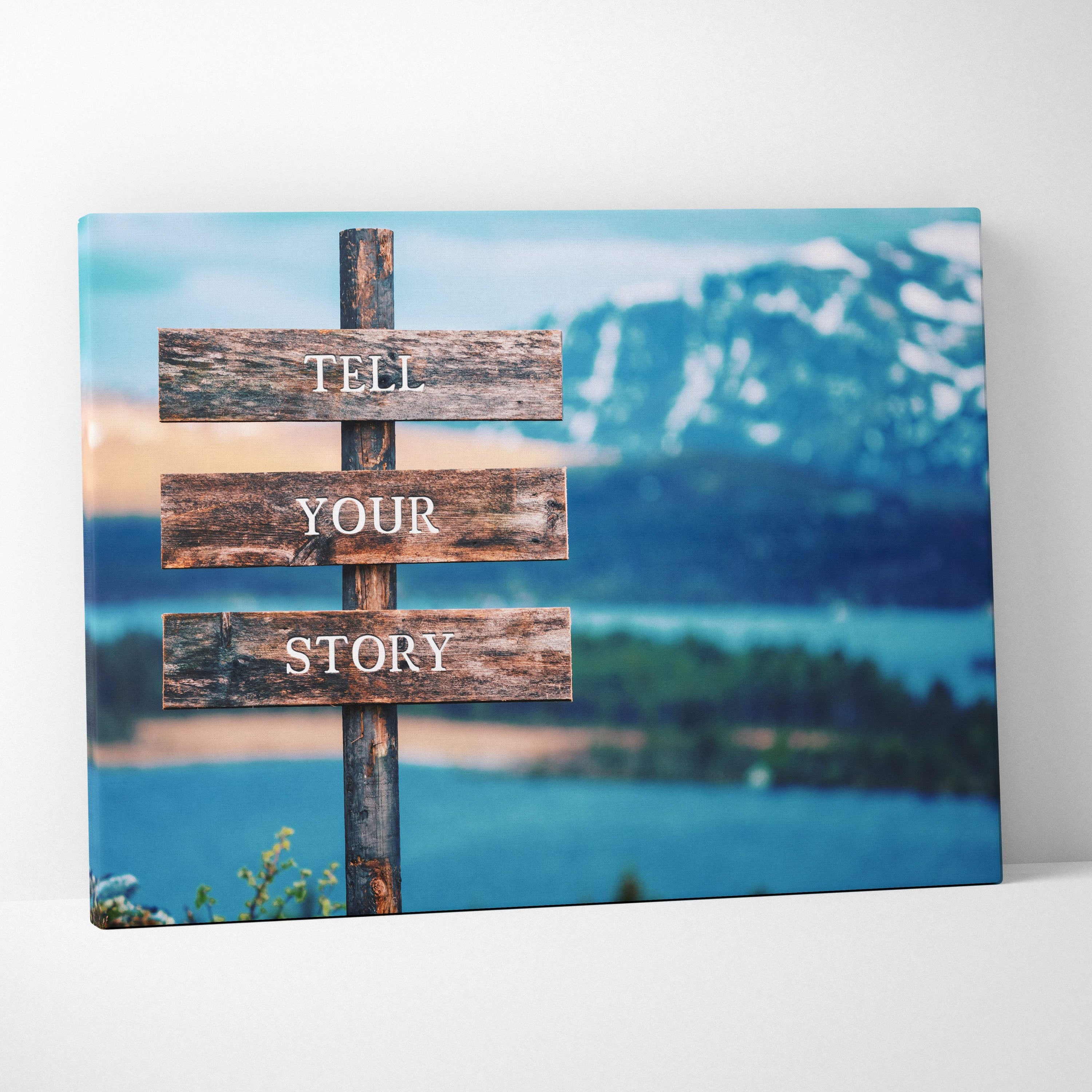 Rustic wooden sign with white lettering reading tell your story against a scenic mountain backdrop for inspirational decor