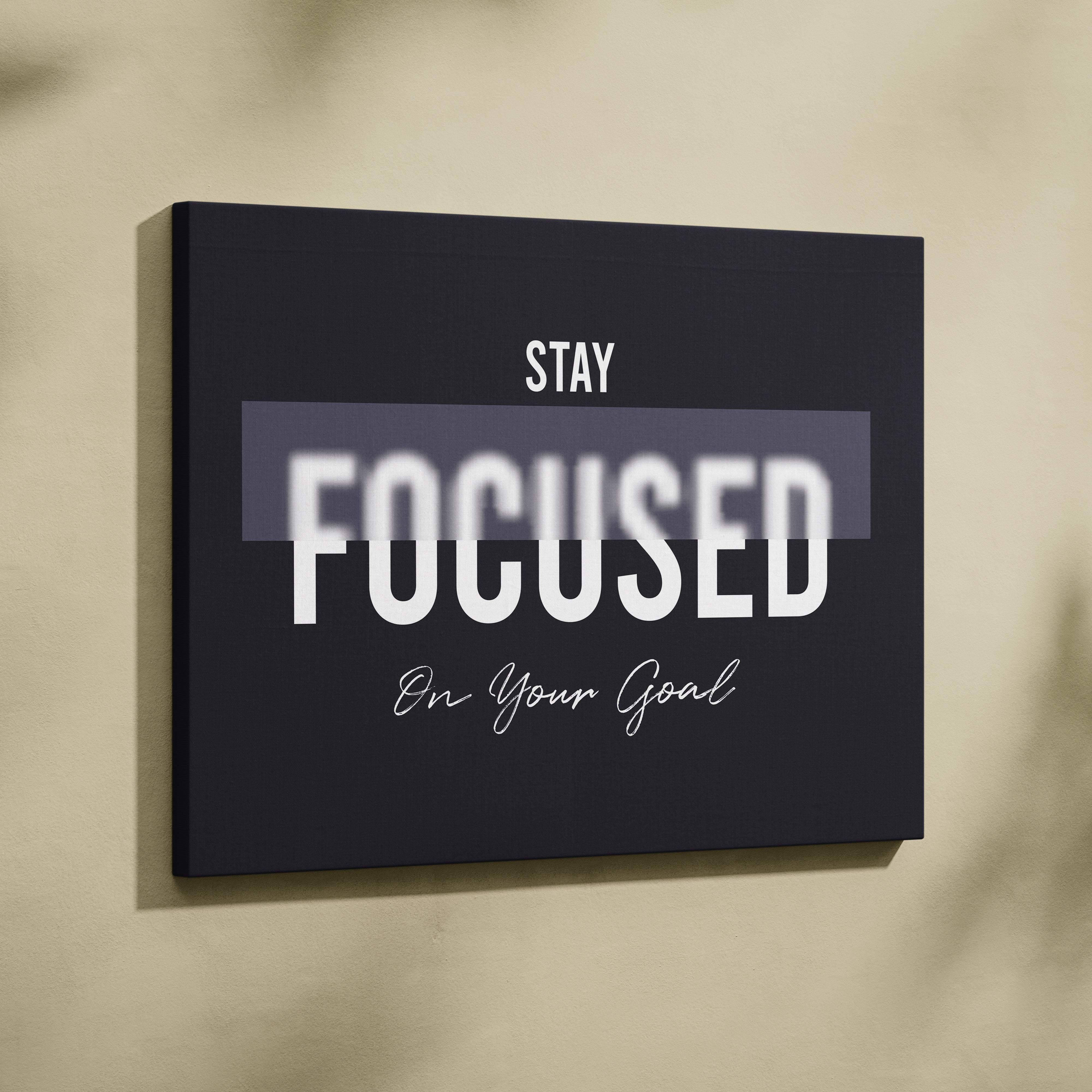Black canvas wall art featuring stay focused on your goal in bold white sans serif and cursive script for office gym decor