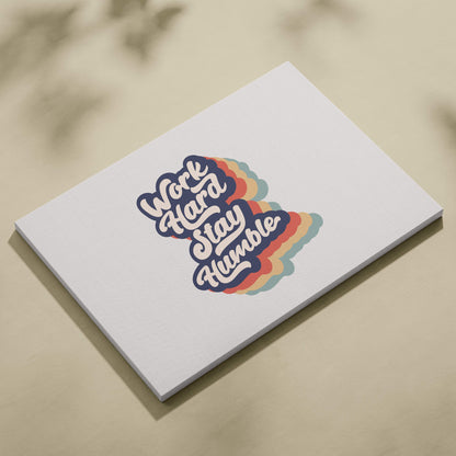White rectangular notepad with colorful retro work hard stay humble graphic and rainbow gradient accents on cover