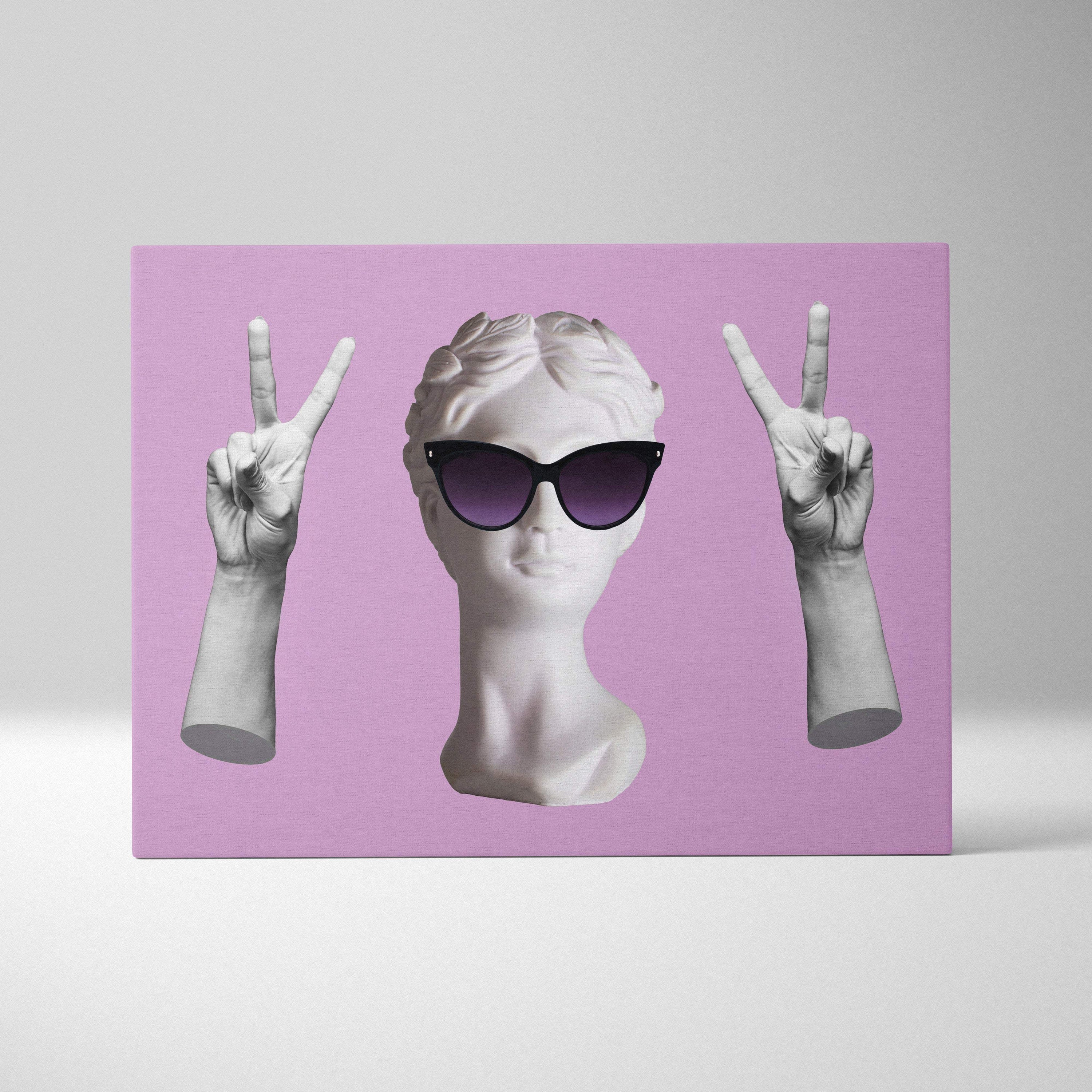 A white marble contemporary bust with black sunglasses and sculpted hands making peace signs on pink wall art