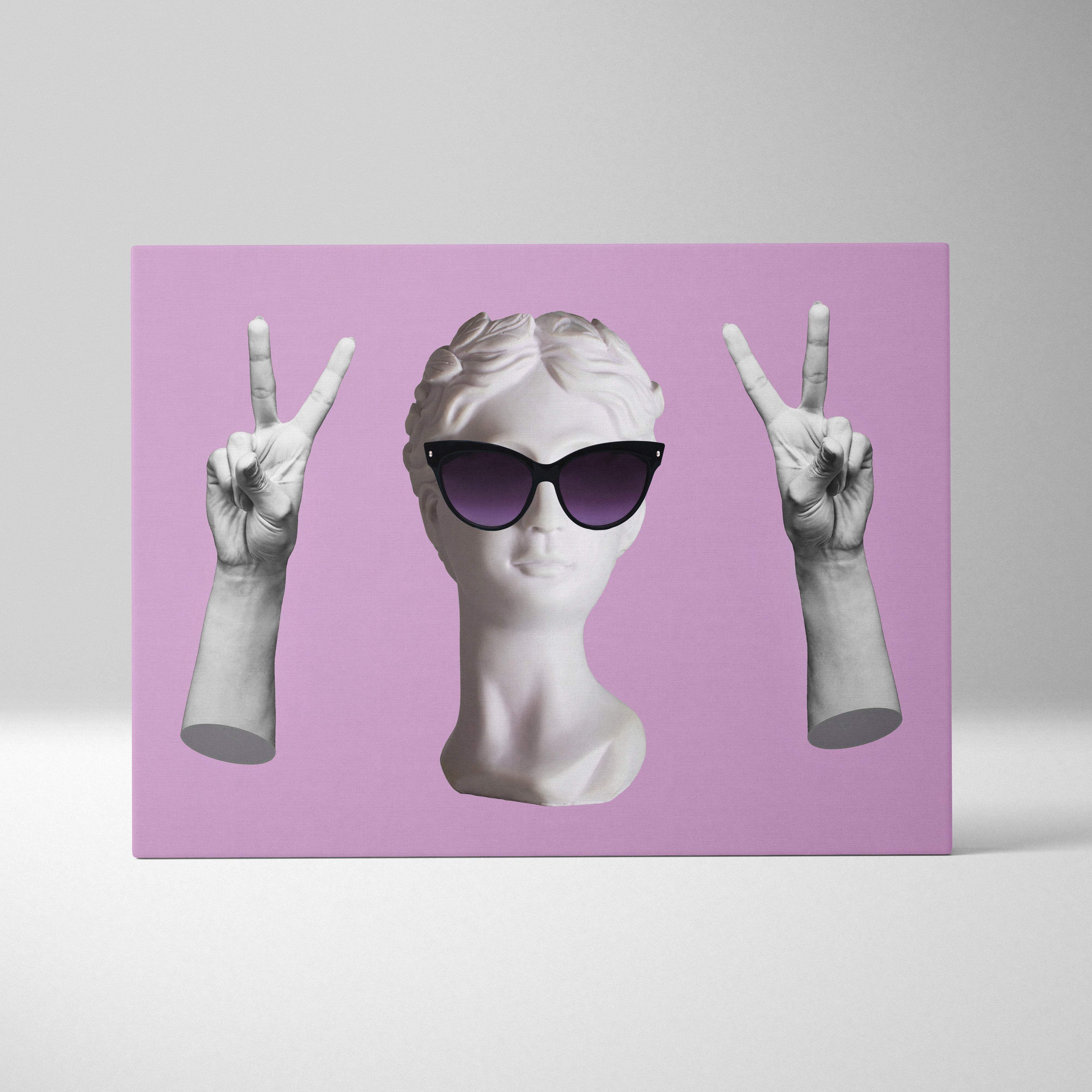 A white marble contemporary bust with black sunglasses and sculpted hands making peace signs on pink wall art