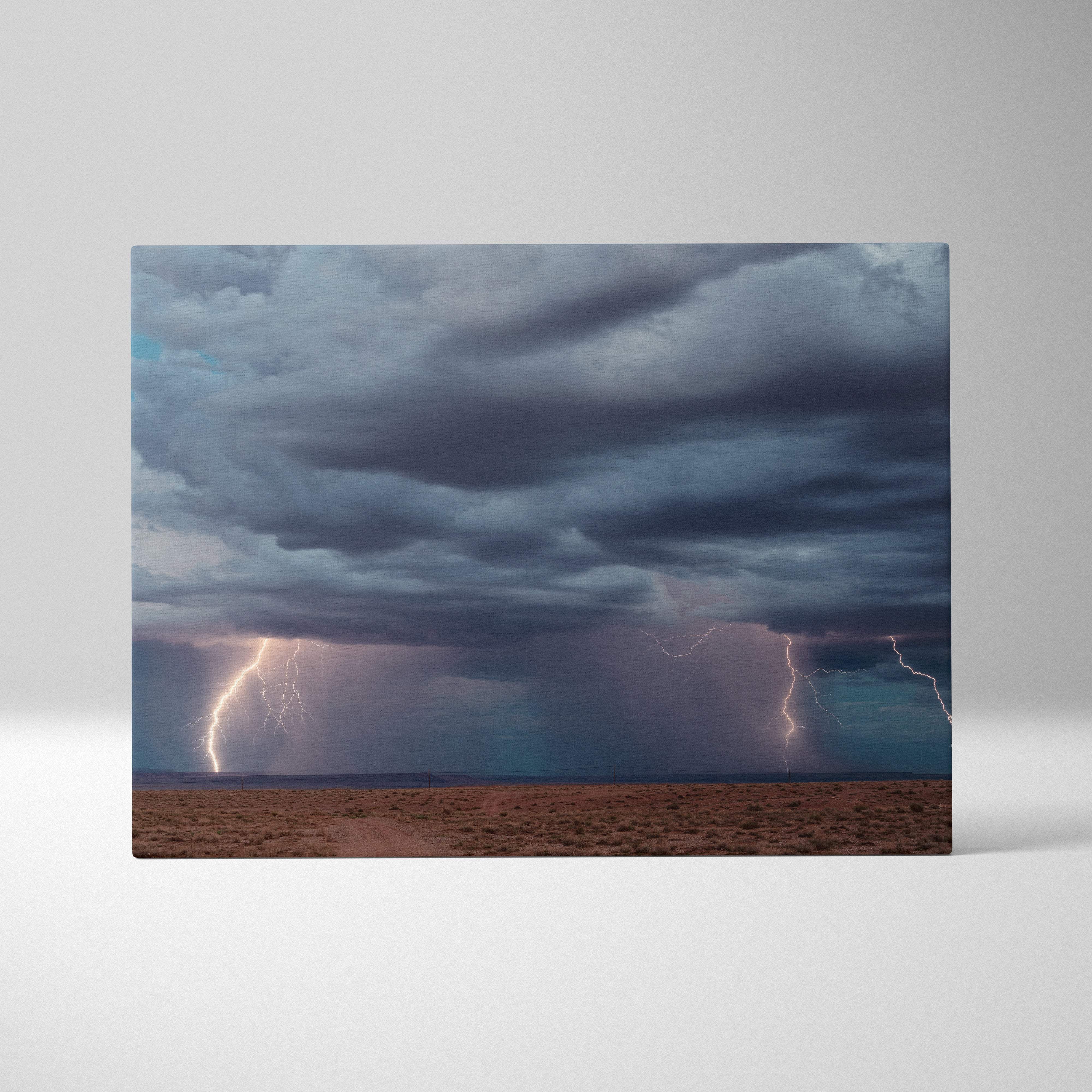 Canvas print of a multiple lightning storm with dark blue thunderclouds over a barren desert landscape wall decor