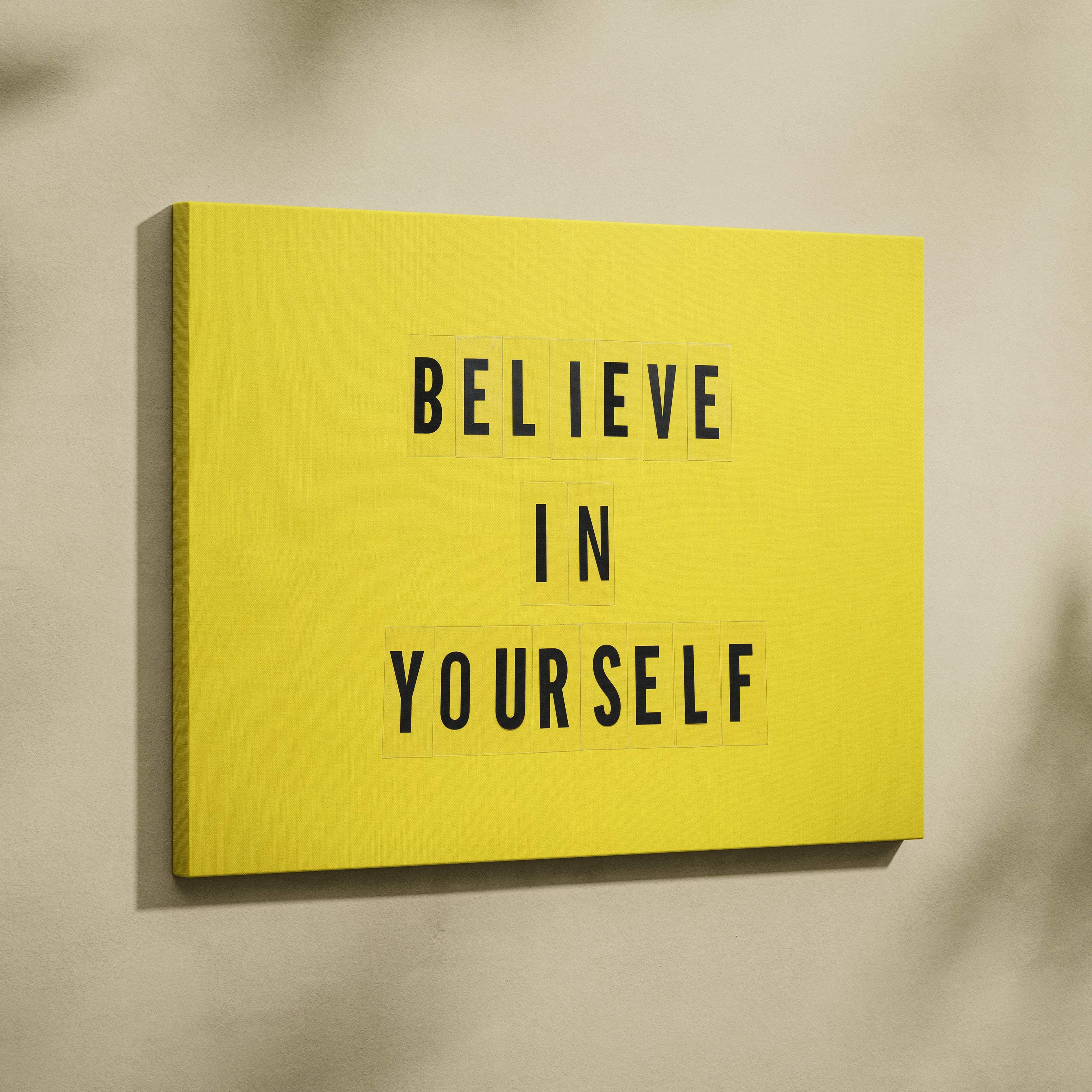 Bright yellow canvas wall art with bold black letter tiles displaying believe in yourself for office or home decor