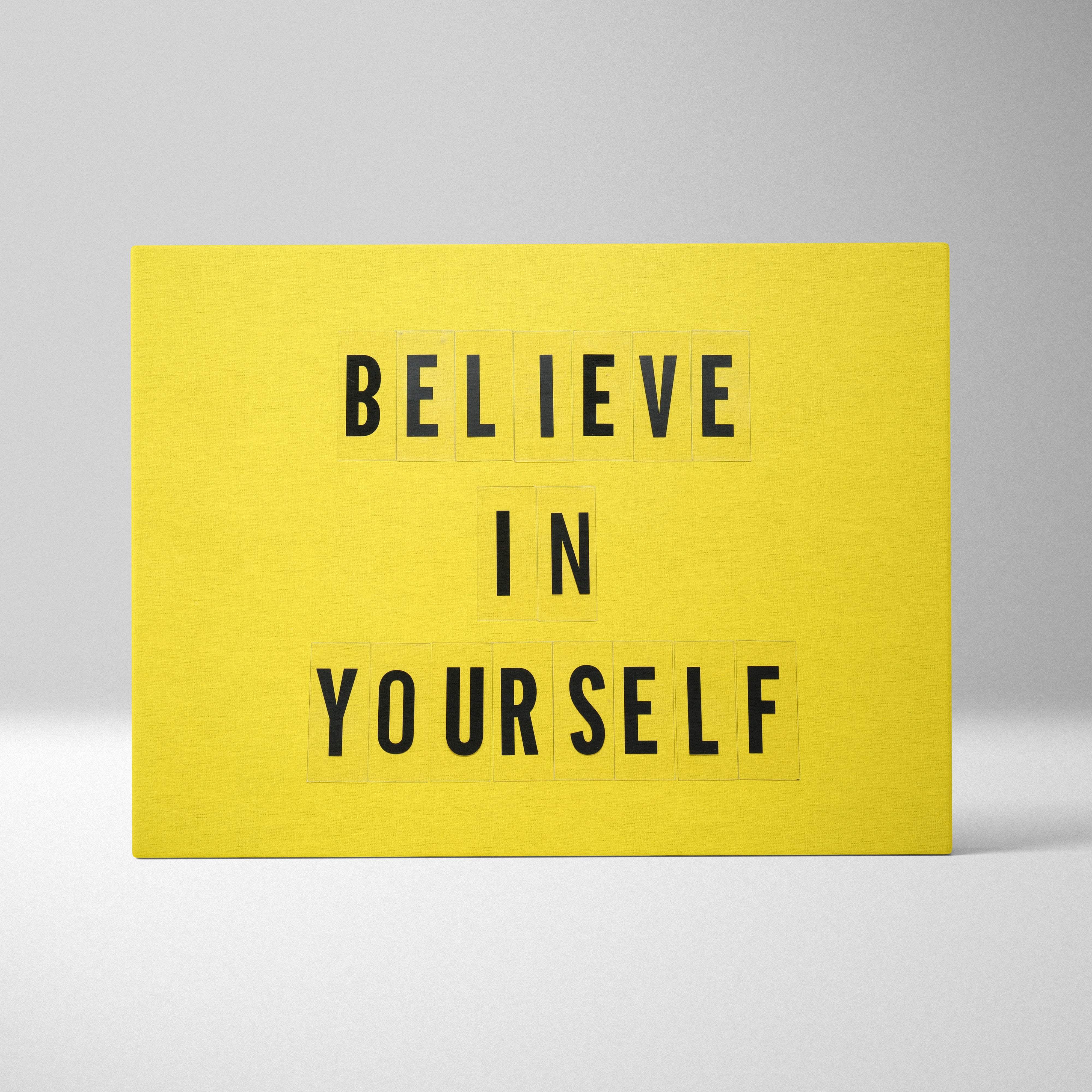 Bright yellow rectangular light box with black letter tiles spelling believe in yourself motivational wall art print