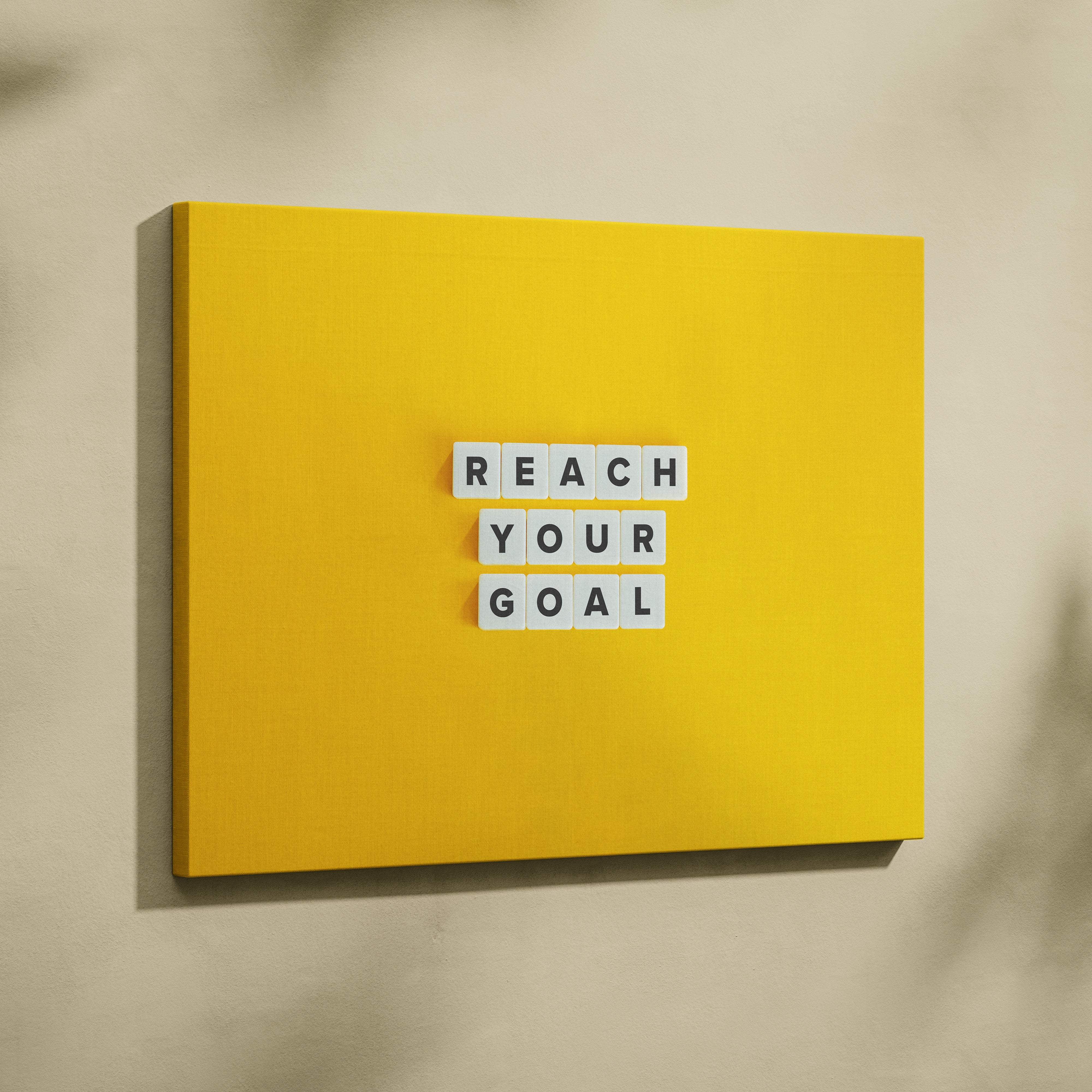 Bright yellow canvas wall art featuring white letter tiles spelling reach your goal motivational quote for office or gym decor