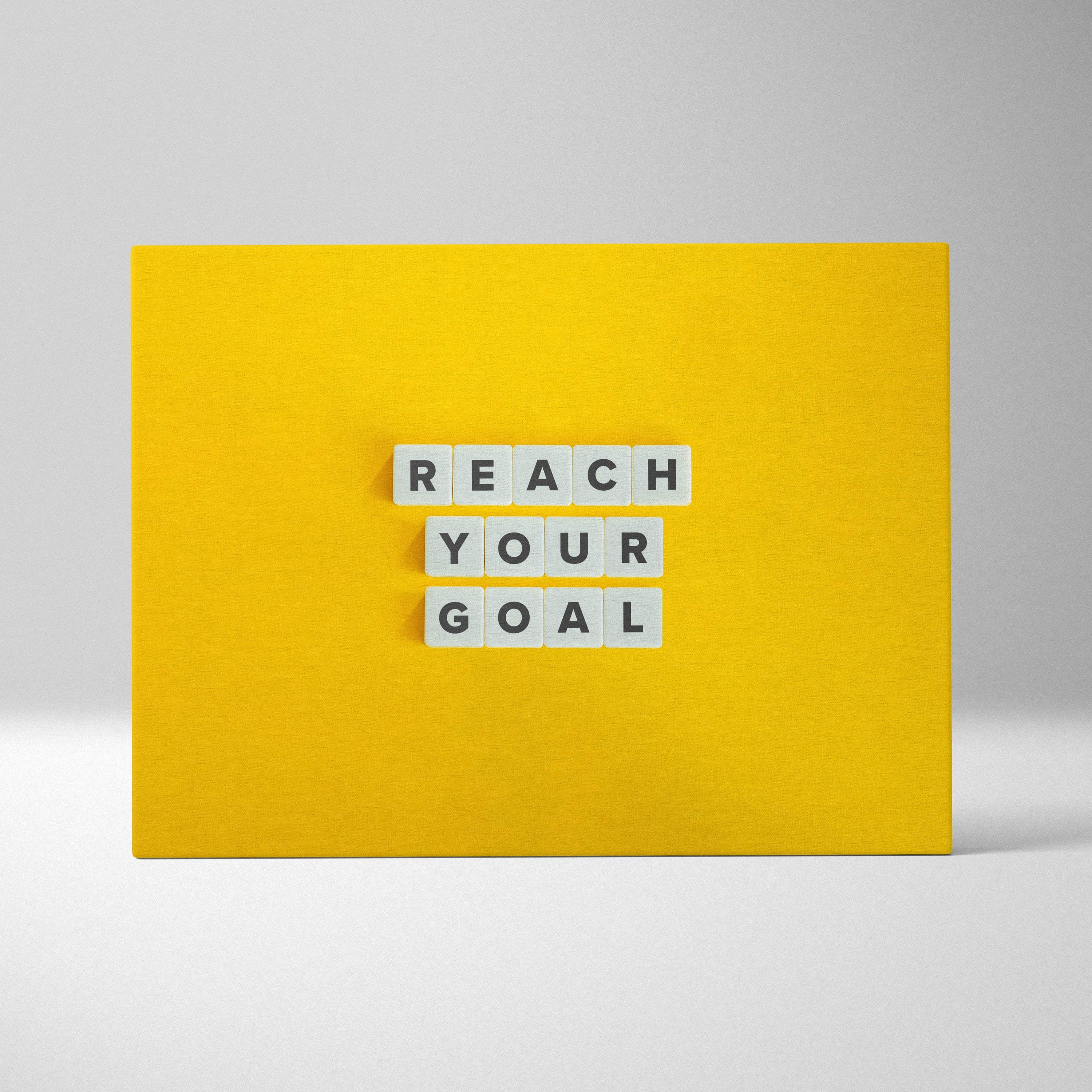 Bright yellow motivational wall art print with reach your goal white letter tiles for office gym or home decor
