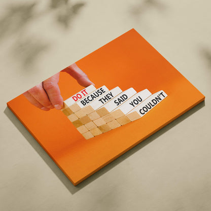 Orange canvas wall art print with wooden blocks arranged in a staircase pattern featuring motivational text