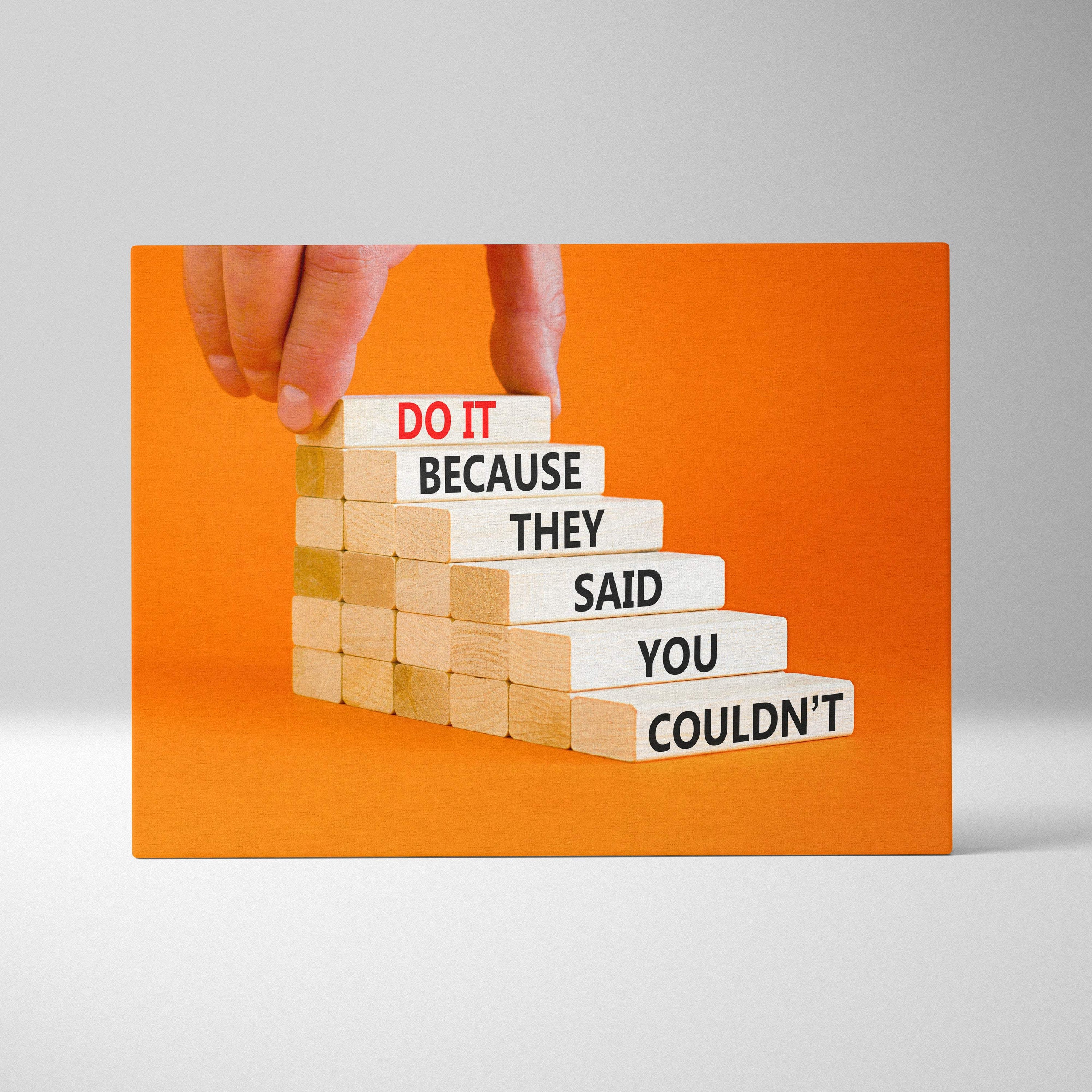 A hand places a white wooden block with red do it text atop motivational quote blocks in inspirational wall art print