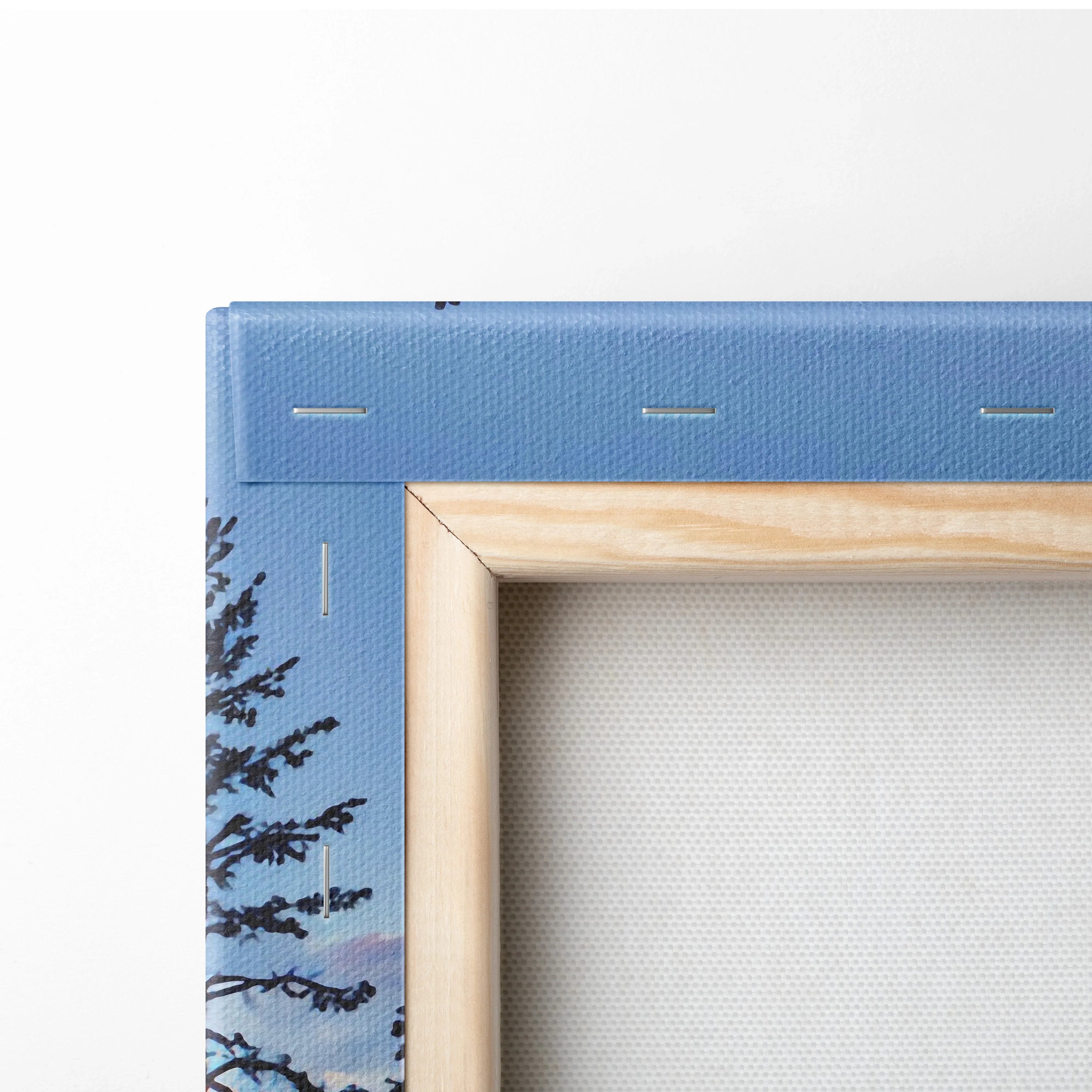 Close-up of canvas wall art corner showing wooden frame and blue snowy forest print detail.