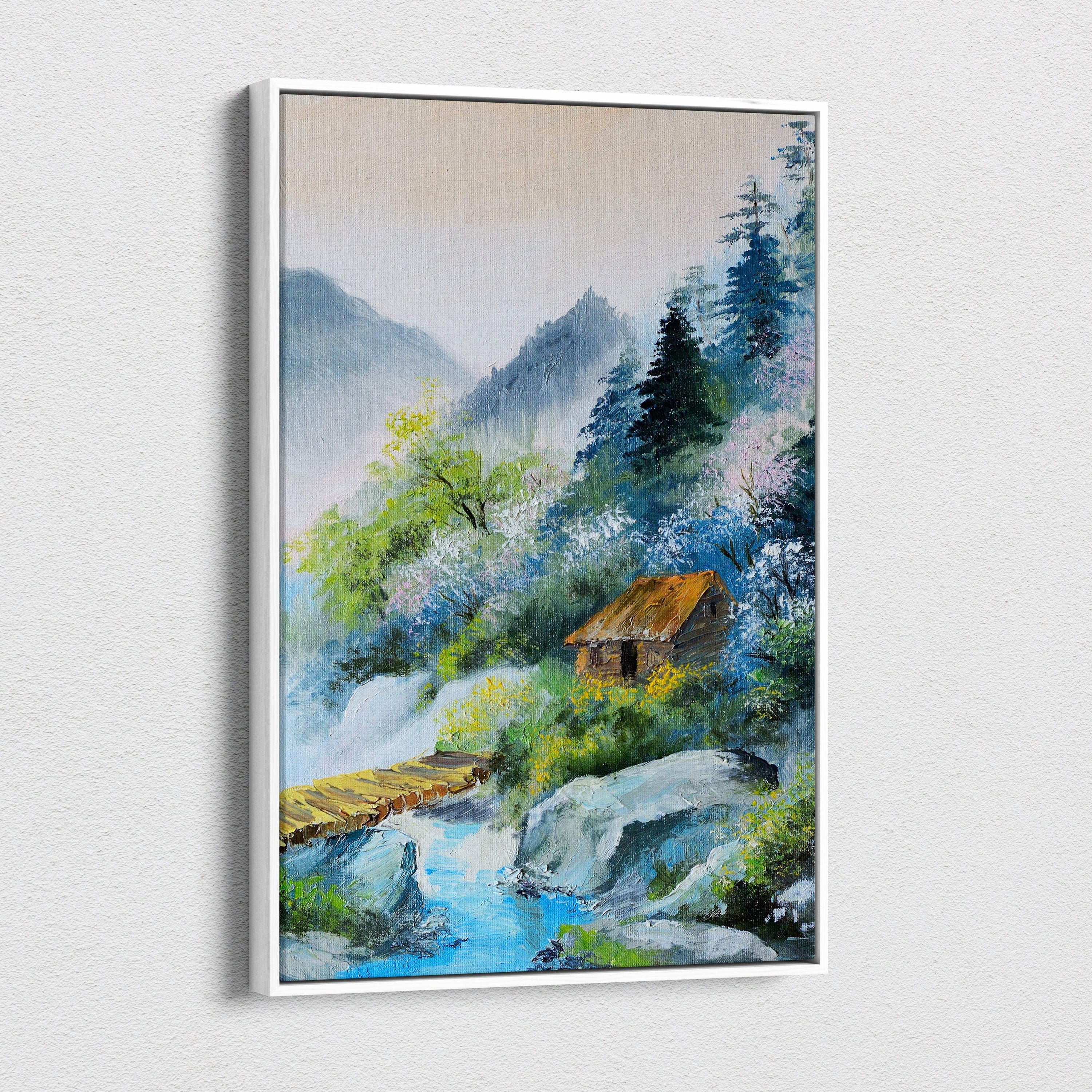 Framed oil painting on canvas of a rustic wooden cabin by a soft blue river amid misty mountains and lush greenery