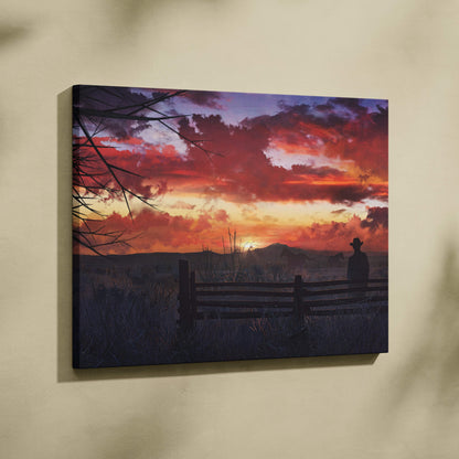 Western sunset canvas print featuring a vibrant red orange and purple sky with a cowboy silhouette by a wooden fence