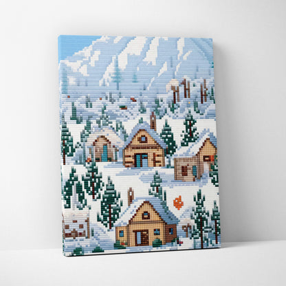 Snowy village pixel art canvas print showing snow-covered wooden houses and evergreen trees with blue mountain backdrop