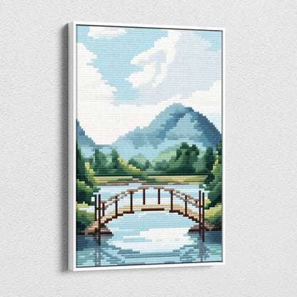 A framed pixel art canvas print of a wooden arched bridge over calm water with mountains and trees under blue sky