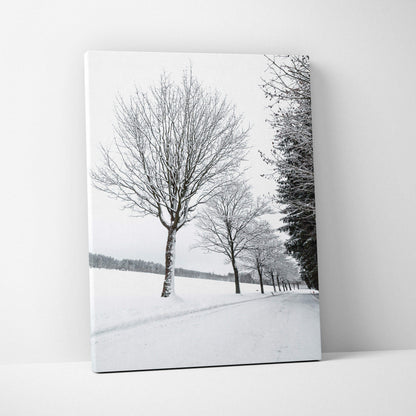 Canvas wall art featuring a row of leafless trees covered in snow against a white winter landscape.