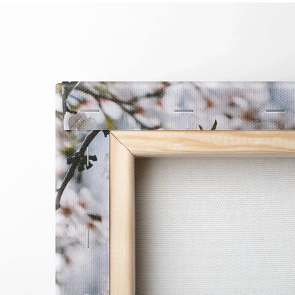 Light wood-framed canvas print of almond blossom branches in soft white pastel mood