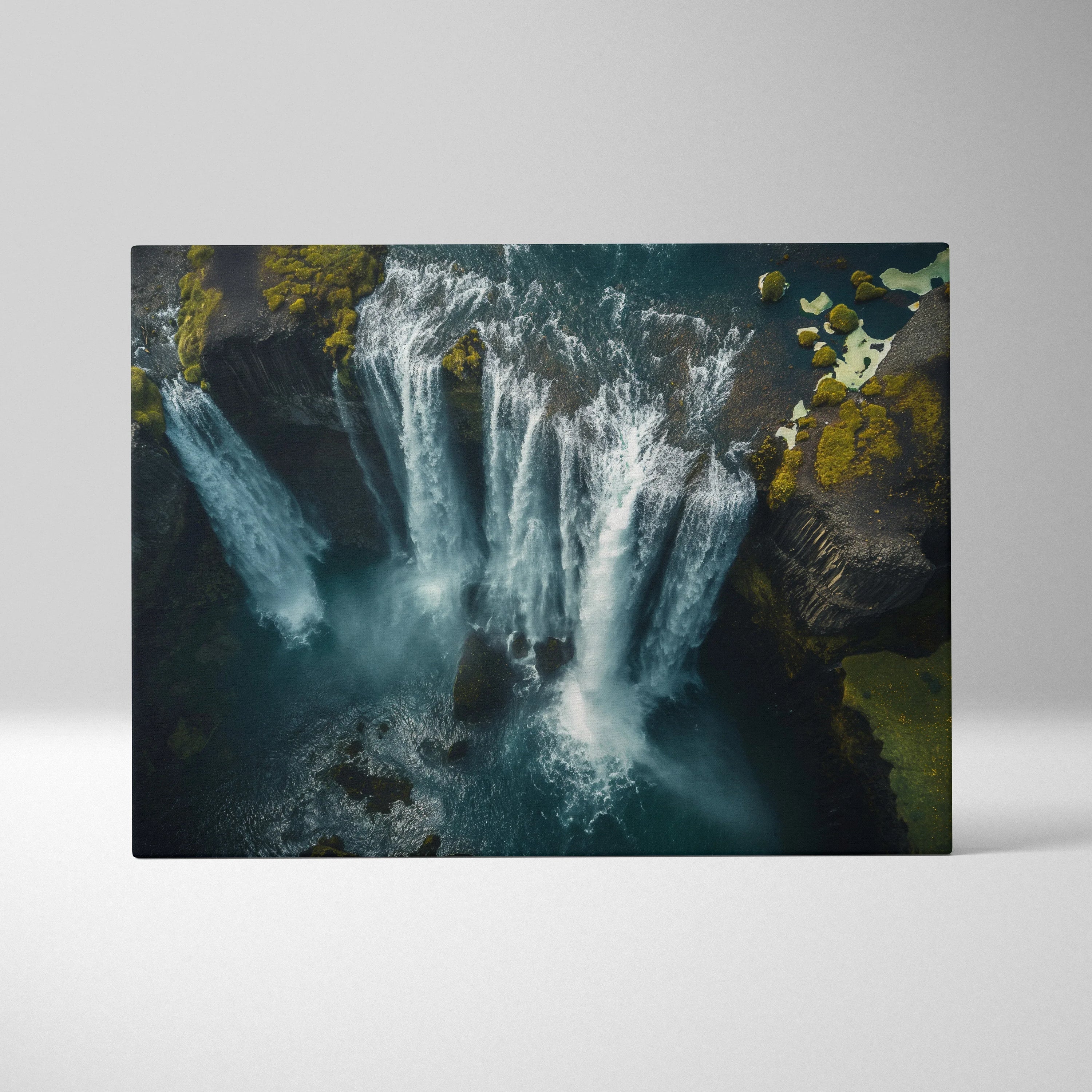 Canvas wall art featuring a high-resolution aerial view of a multi-tiered Icelandic waterfall surrounded by dark rocky.