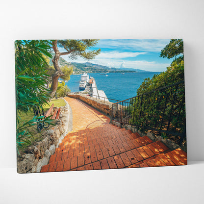 Canvas wall art depicting a sunlit brick pathway by the sea with lush greenery and blue sky.